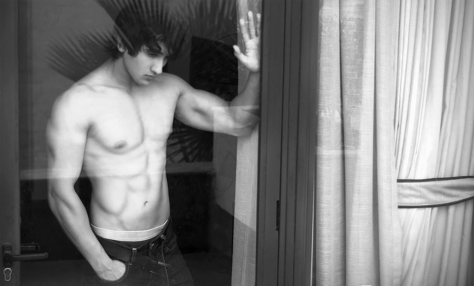 Ein Mann ohne Hemd, der am Fenster steht | Quelle: Pexels
