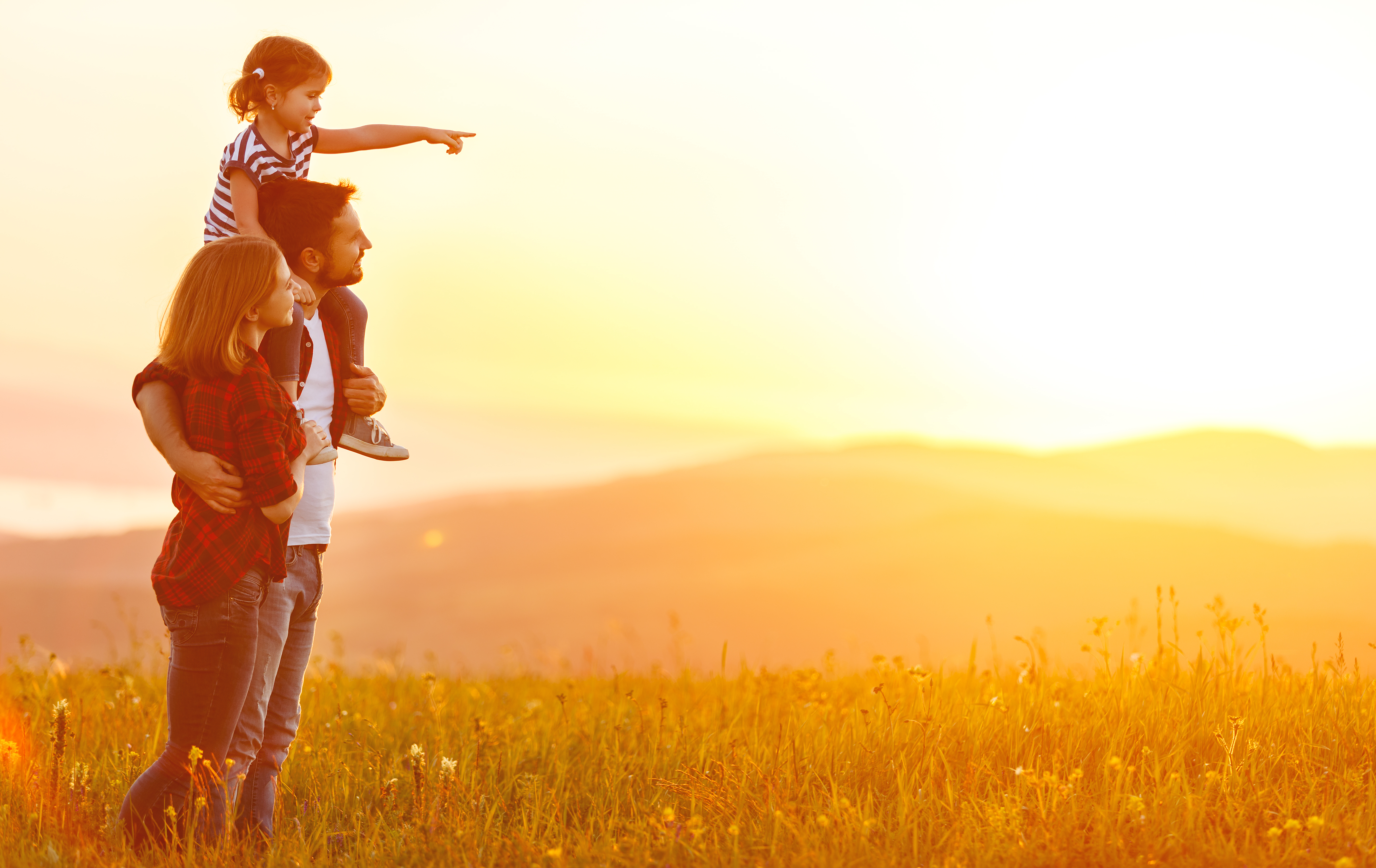 Paar, das mit seiner kleinen Tochter den Sonnenuntergang beobachtet | Quelle: Shutterstock
