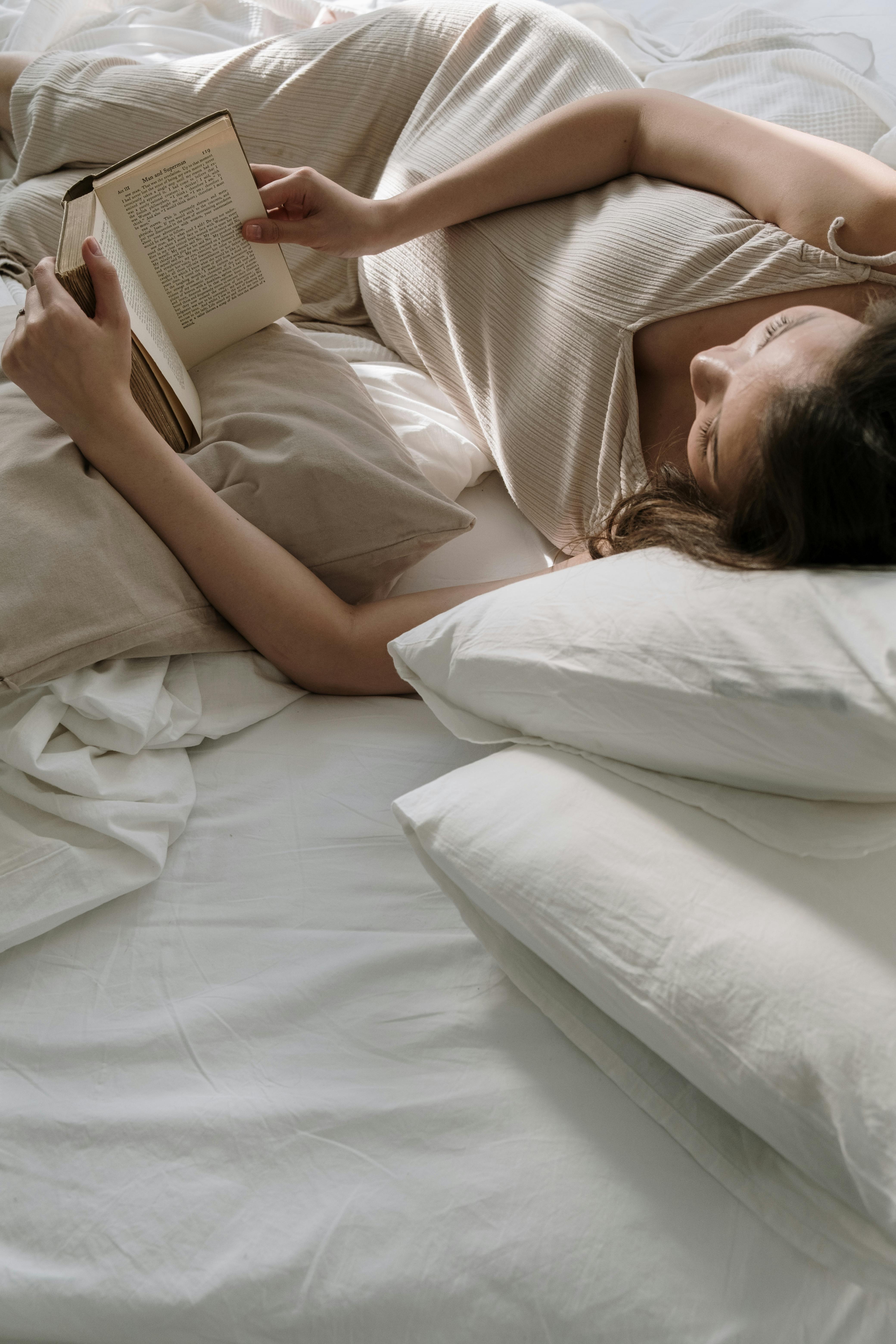 Eine Frau liegt im Bett und liest ein Buch | Quelle: Pexels
