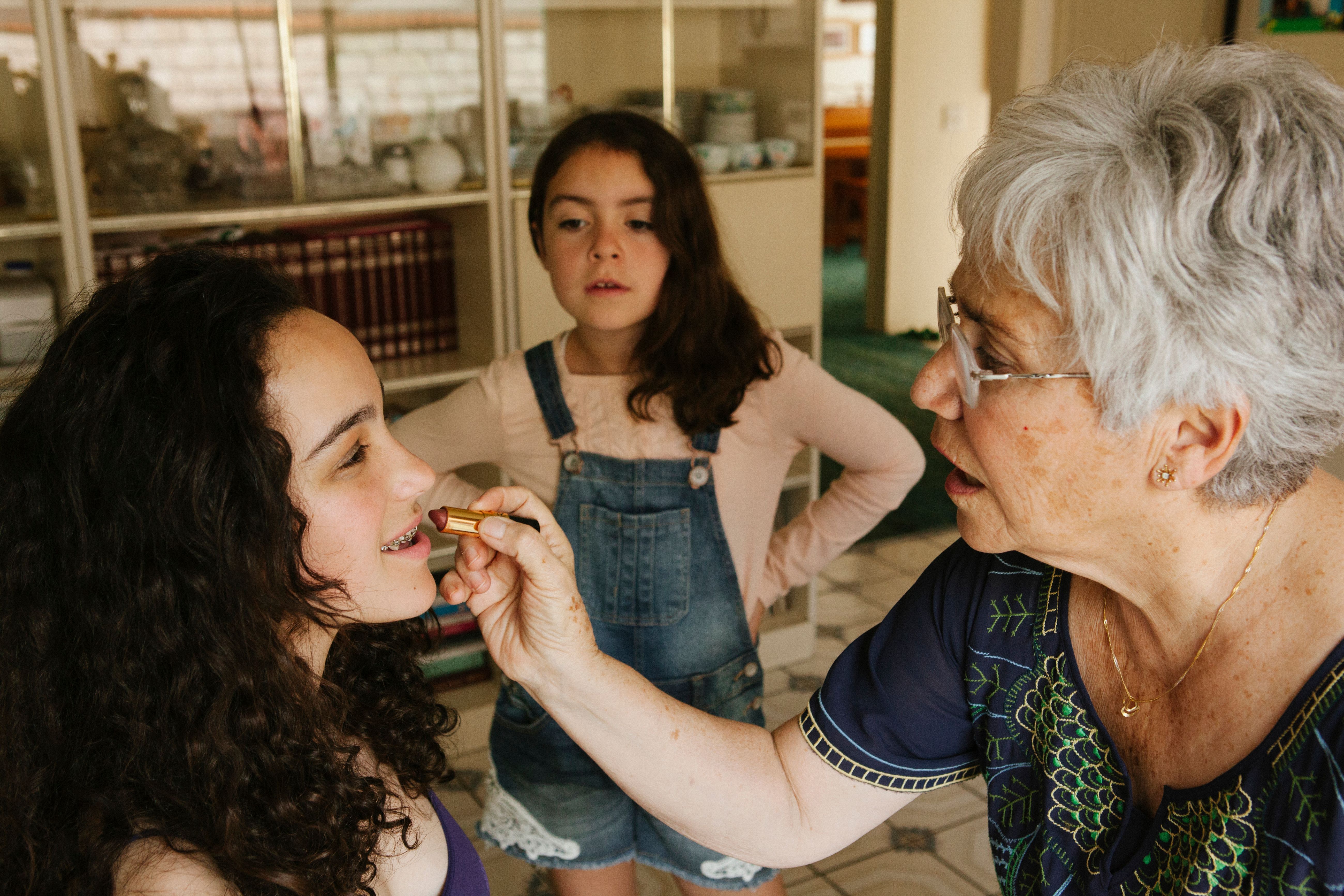 Eine Großmutter, die ihrer Enkelin Lippenstift aufträgt | Quelle: Getty Images