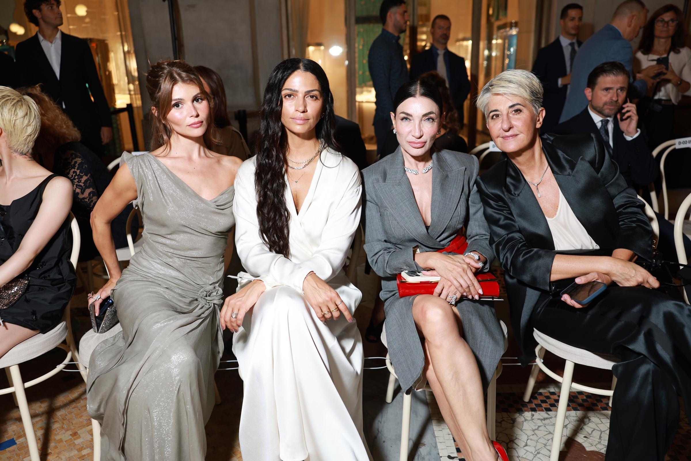 Alves sitzt neben Olivia Jade und Elisabetta Franchi und blickt in die Kamera, während ihre mehrreihigen Halsketten und der tief ausgeschnittene Wickelausschnitt im Mittelpunkt stehen. | Quelle: Getty Images