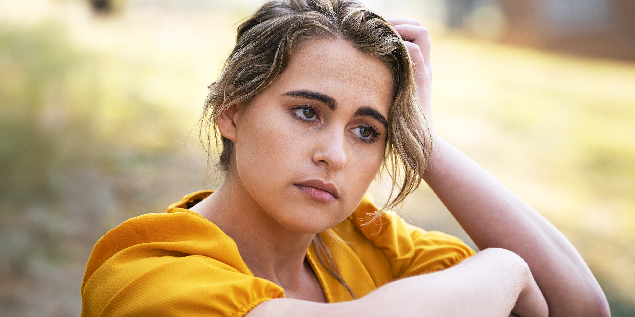 Eine junge Frau in einem gelben Kleid, die in Gedanken versunken ist | Quelle: Freepik