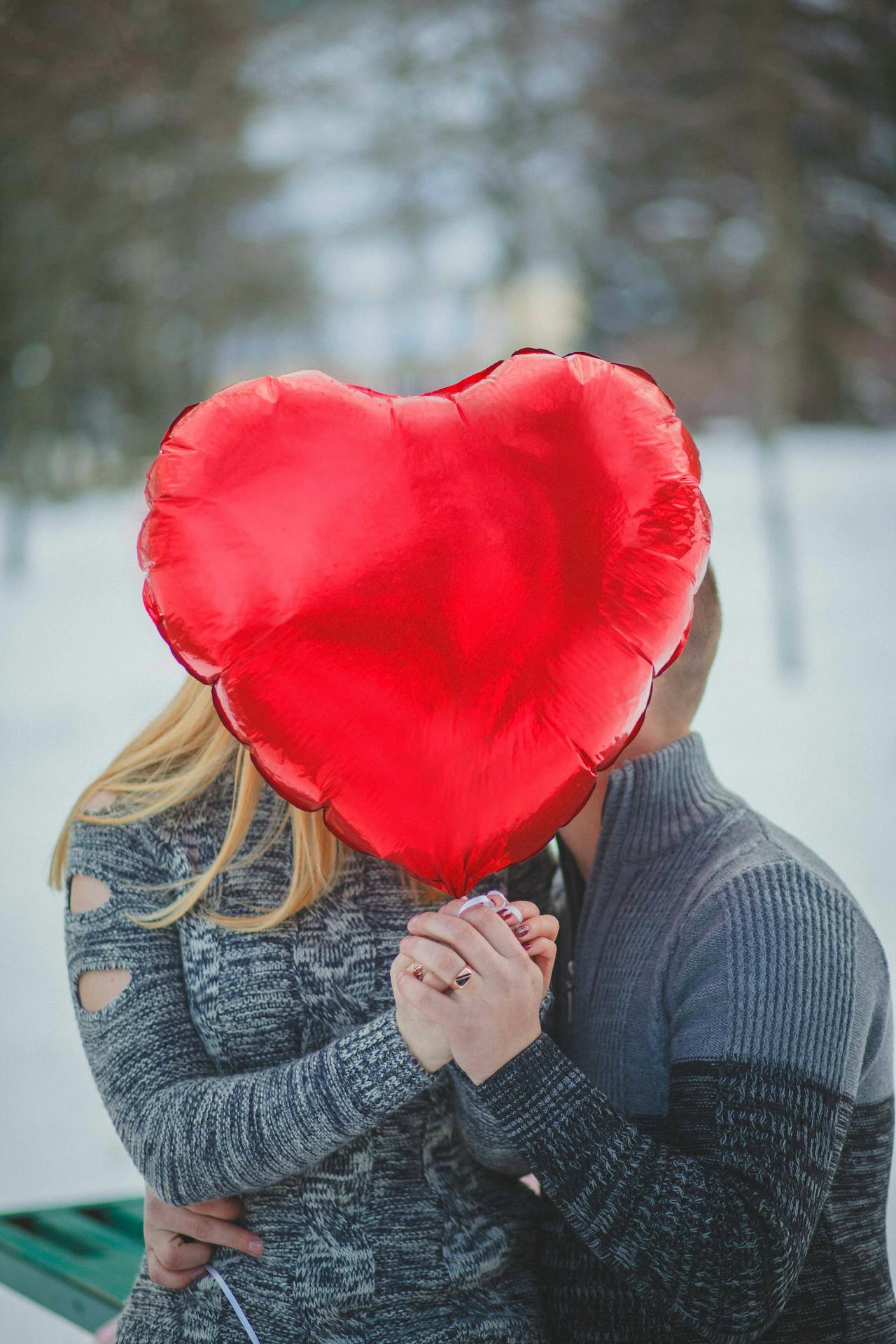 Ein romantisches Paar, das einen roten herzförmigen Ballon hält | Quelle: Pexels