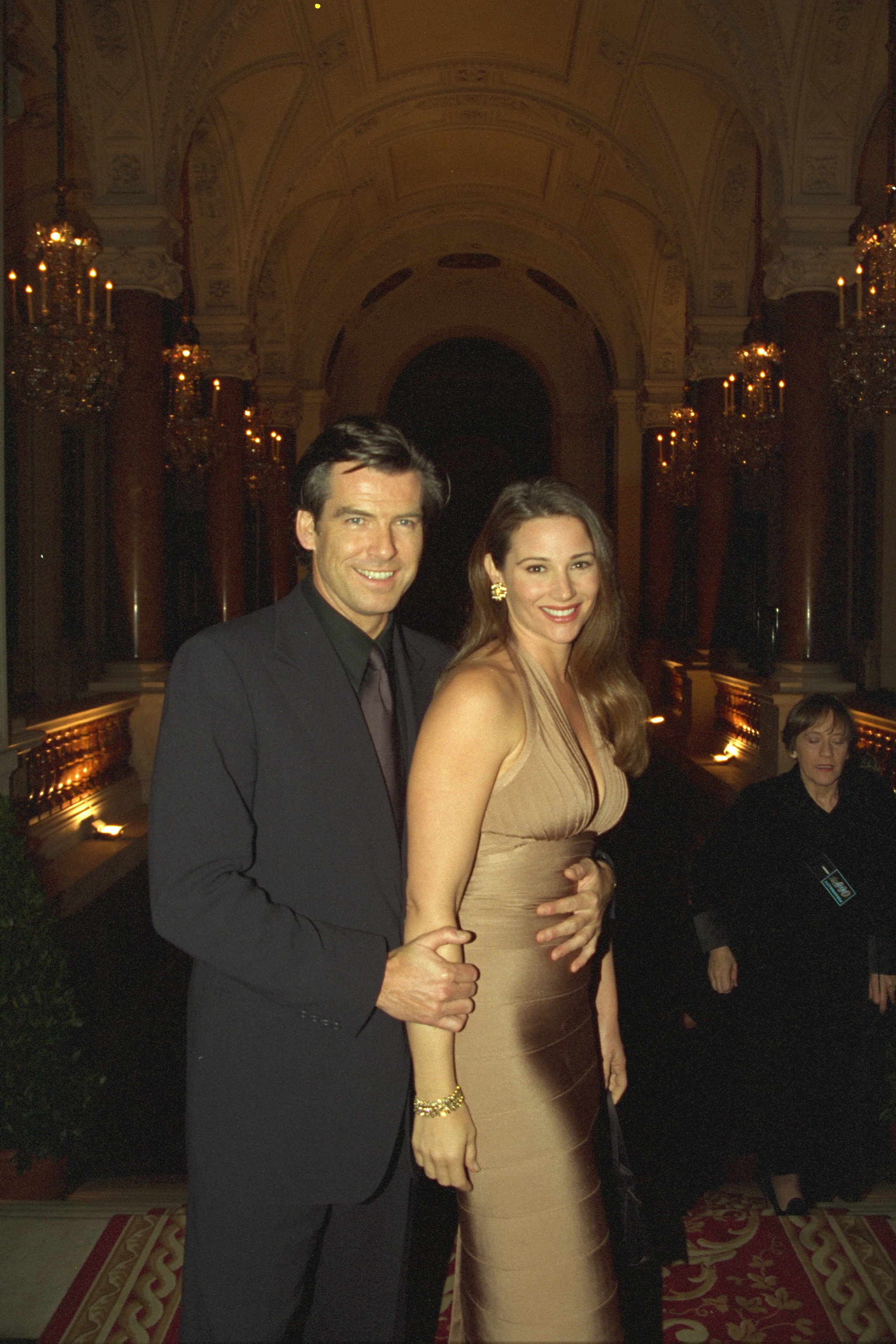 Die schwangere Keely Shaye Smith posiert mit Pierce Brosnan, der liebevoll eine Hand auf ihren wachsenden Babybauch legt – nur wenige Monate, bevor das Paar seinen Sohn willkommen hieß. | Quelle: Getty Images.