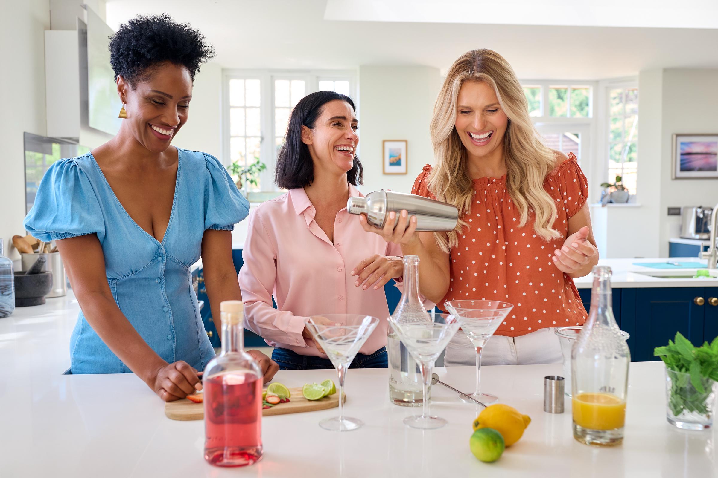 Drei Freundinnen, die Spaß daran haben, gemeinsam Cocktails zu mixen | Quelle: Getty Images
