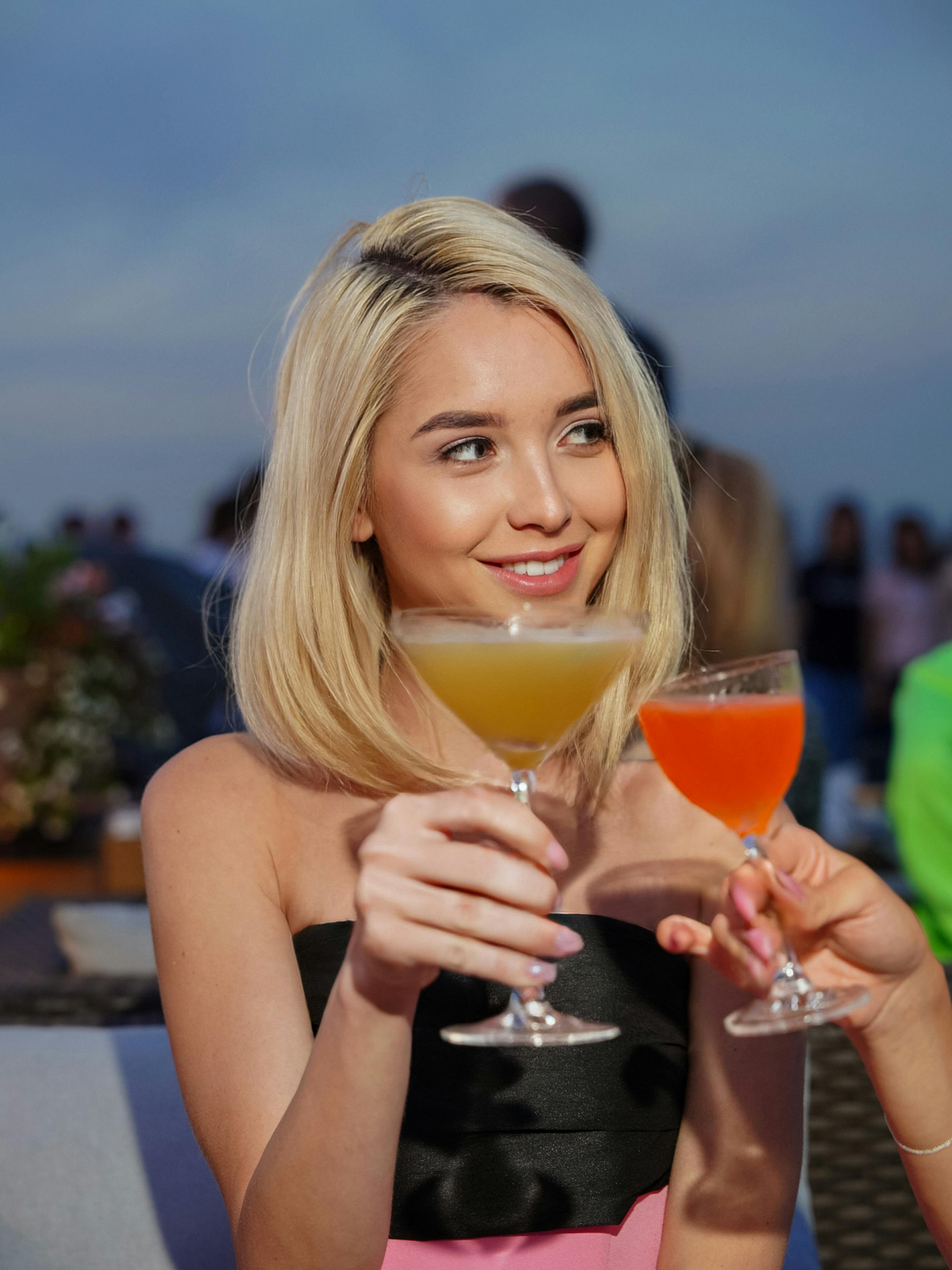 Blondine mit einem Cocktail bei einem Toast | Quelle: Pexels