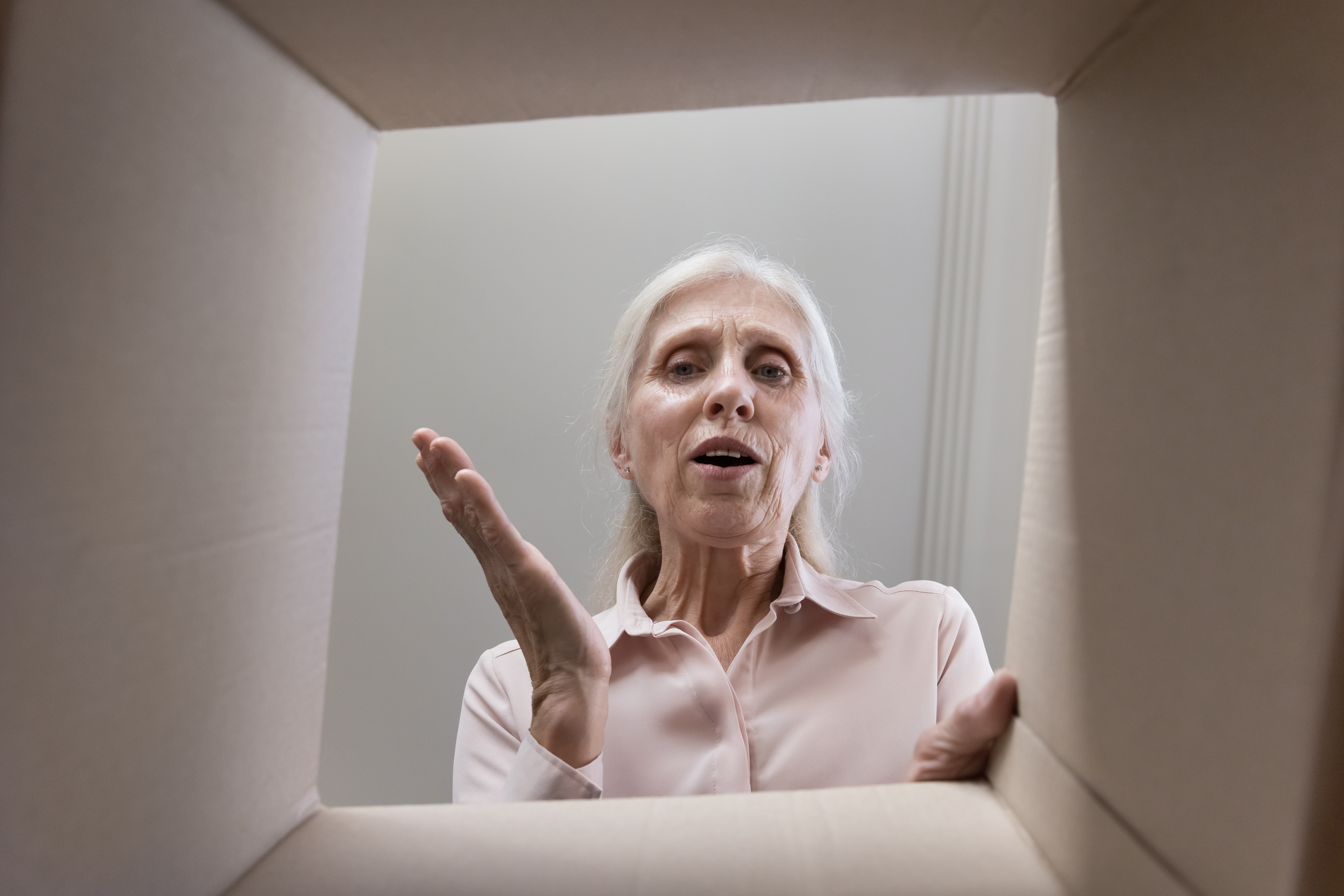 Ältere Frau schaut in einen Karton | Quelle: Shutterstock