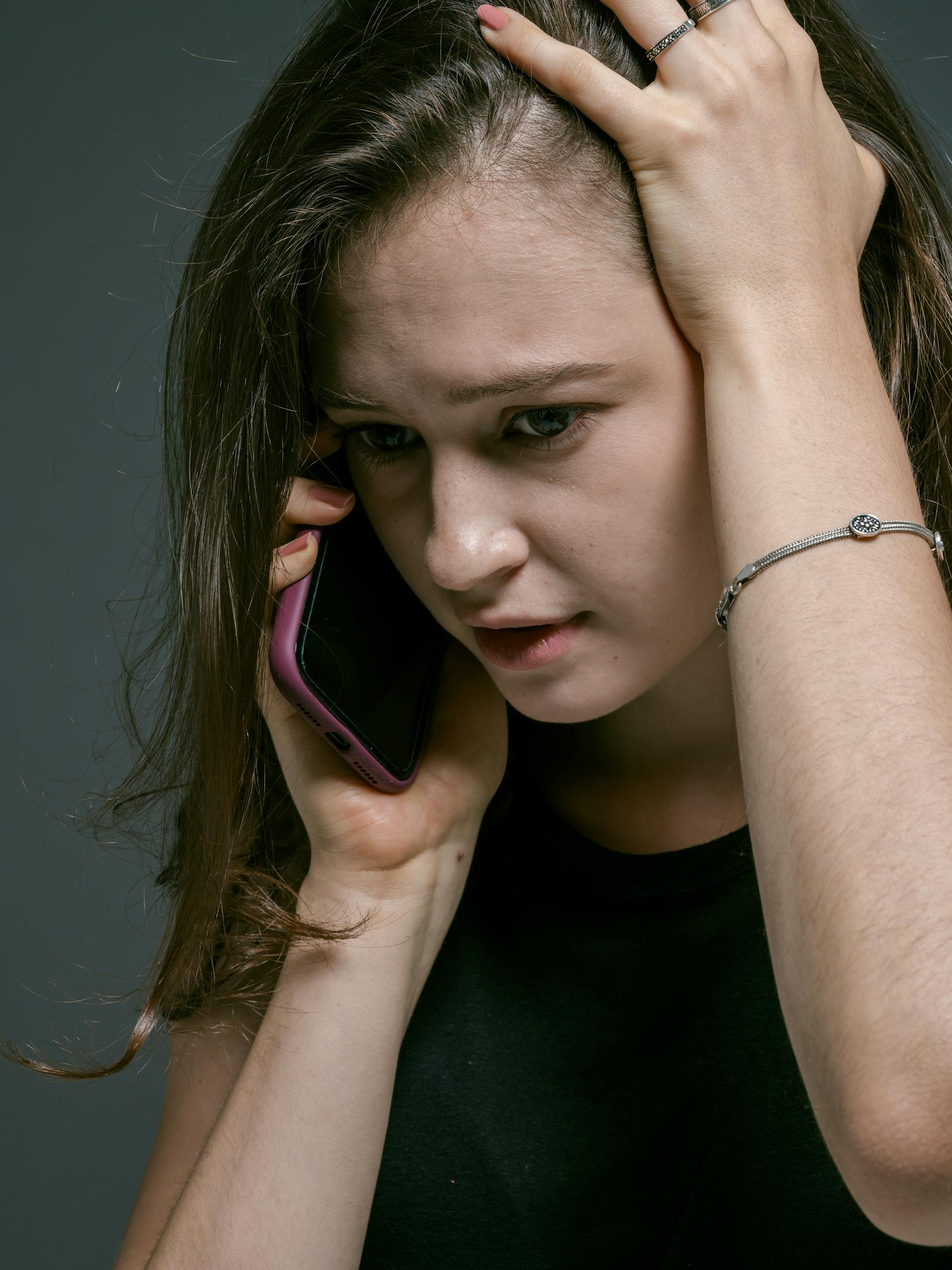Eine Frau am Handy mit der Hand auf dem Kopf | Quelle: Pexels