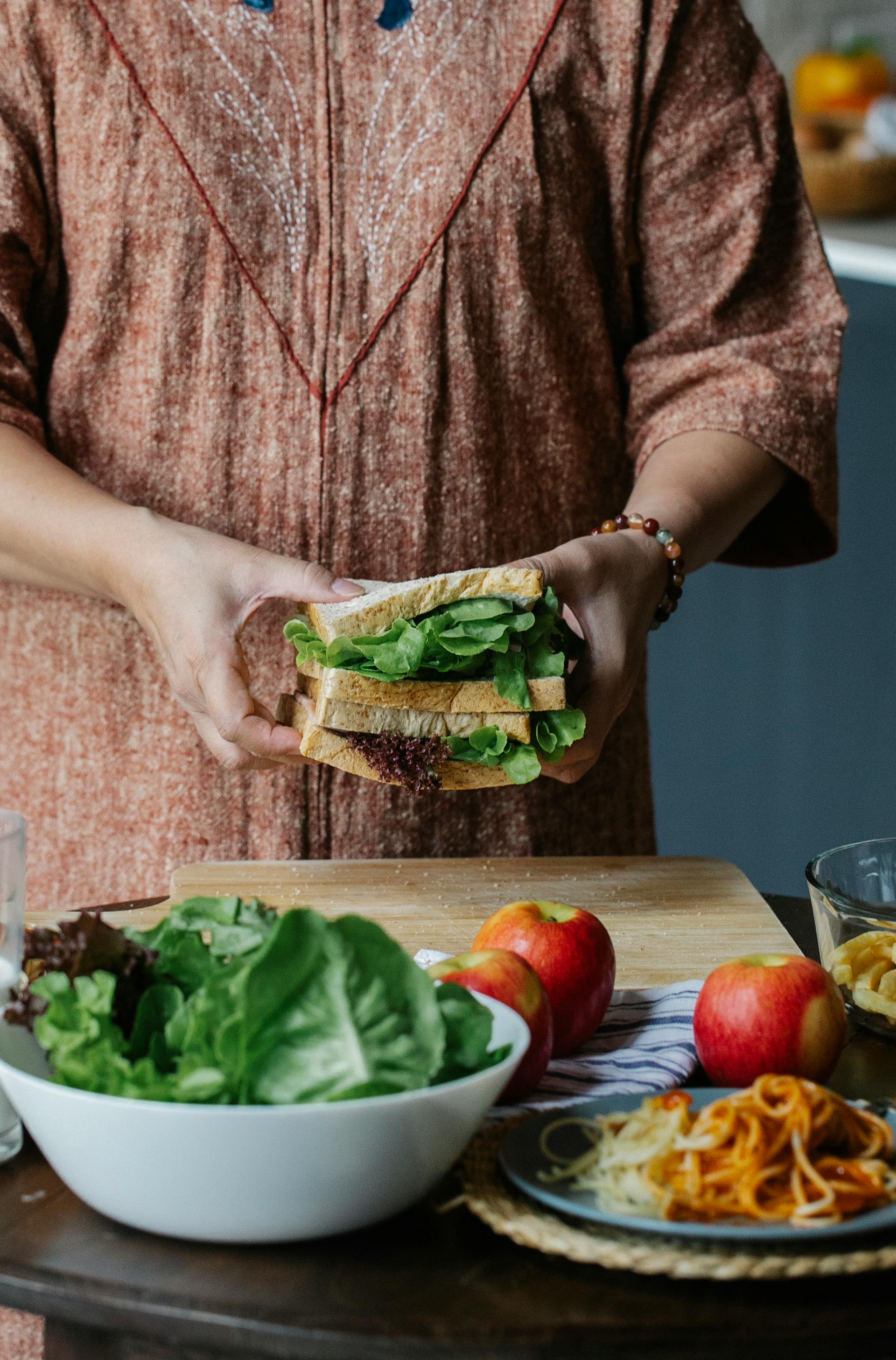 Eine Nahaufnahme einer Frau, die in der Küche ein Sandwich zubereitet | Quelle: Pexels