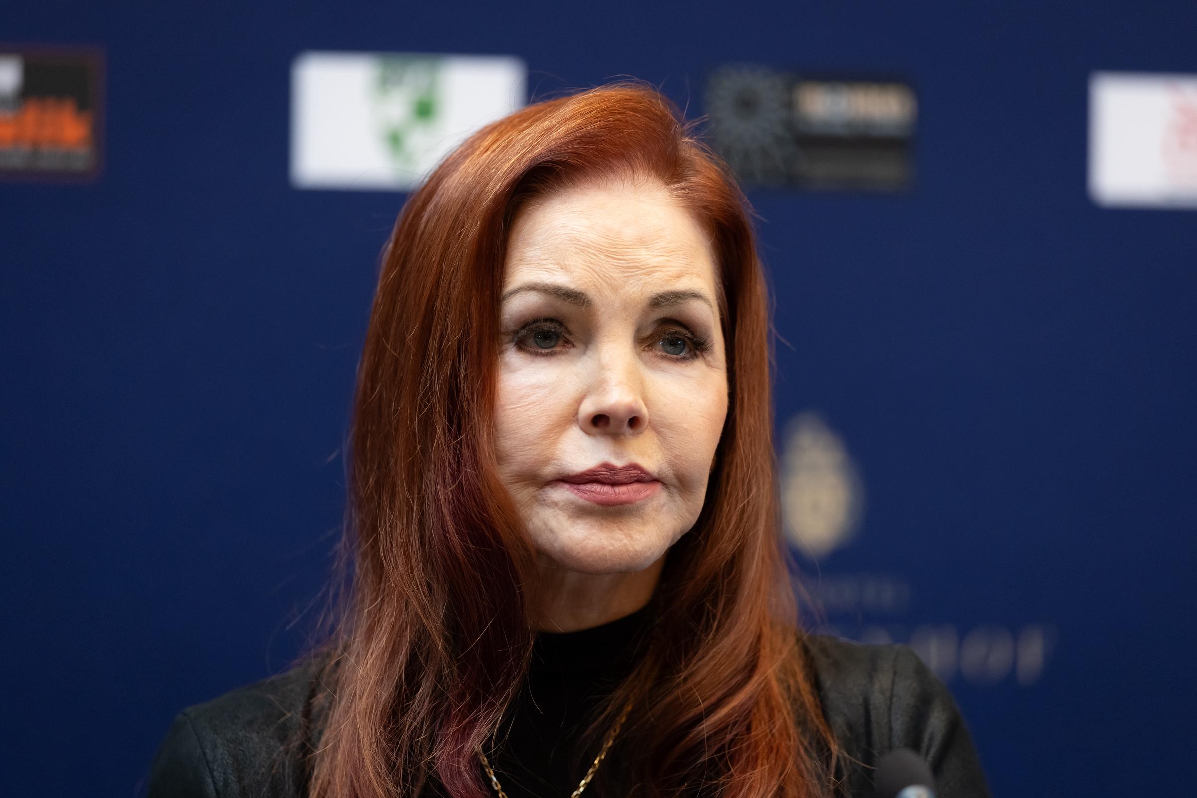 Priscilla Presley nimmt am 20. Oktober 2026 bei einem Besuch in Baesweiler an einer Veranstaltung teil. Sie trägt ein schwarzes Rollkragenoberteil, das durch eine zarte goldene Halskette ergänzt wird, und ihr charakteristisches rotbraunes Haar ist glatt frisiert und hat einen tiefen Seitenscheitel. | Quelle: Getty Images