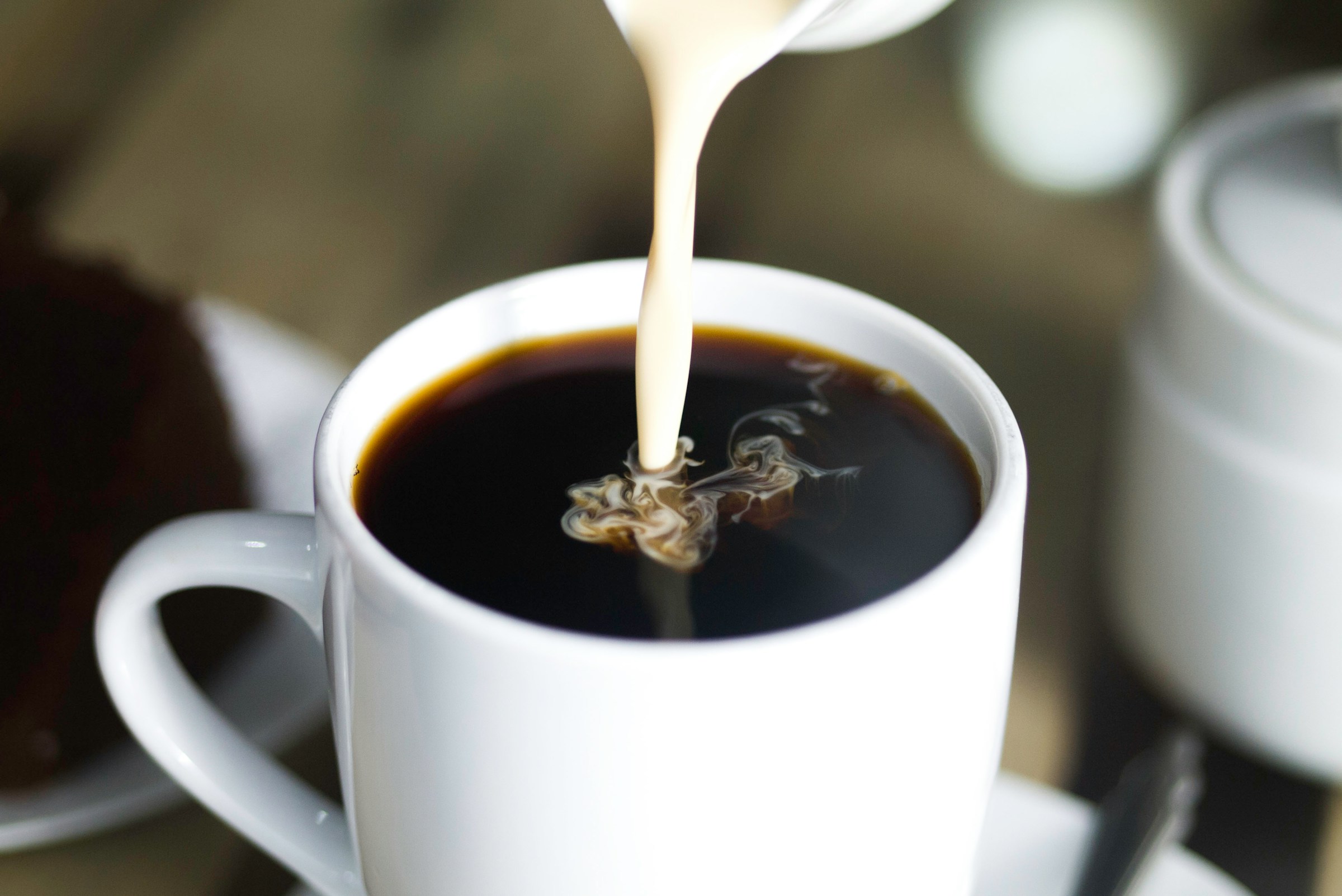 Eine Person gießt Milch in den Kaffee | Quelle: Unsplash