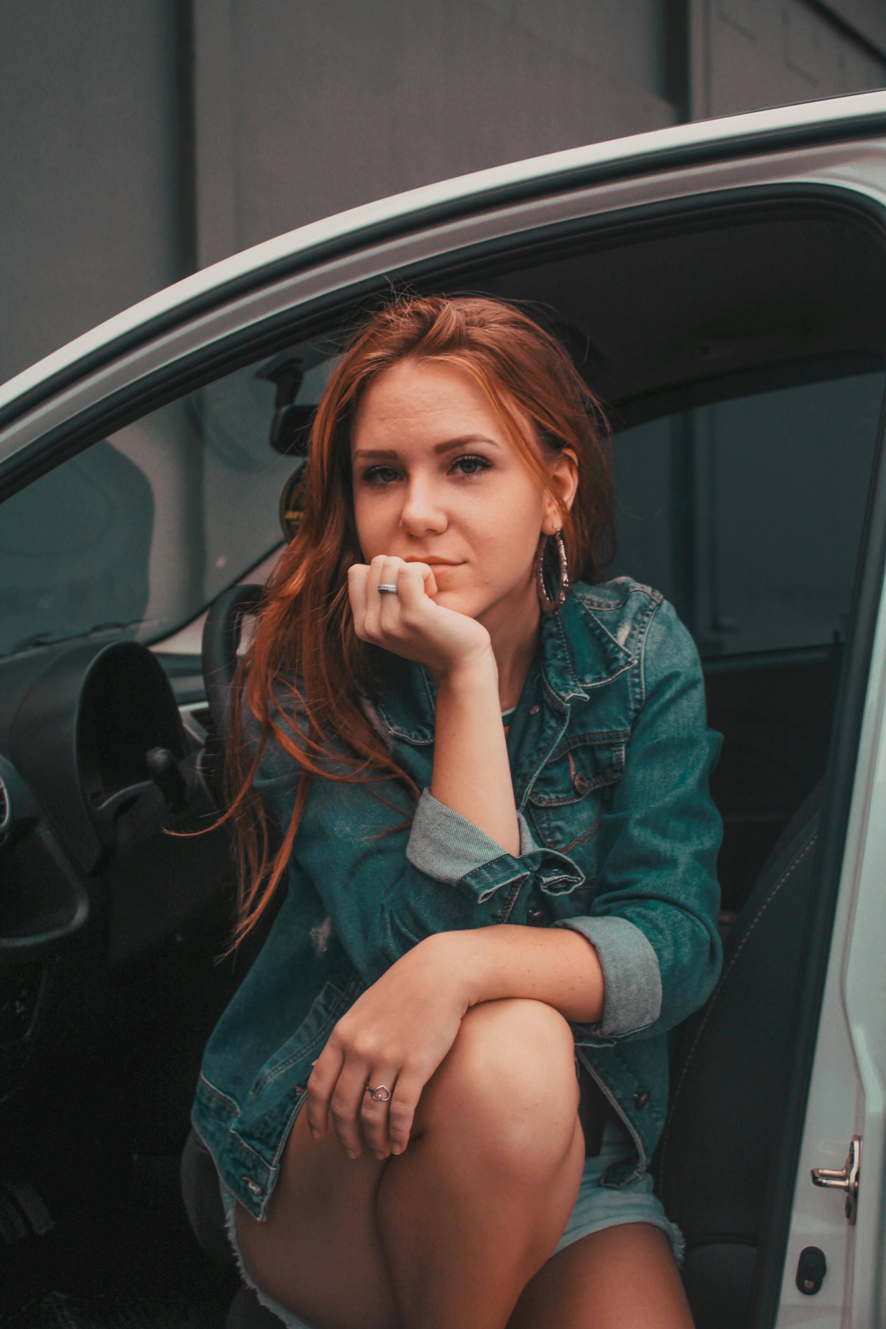 Eine Frau, die mit offener Autotür sitzt und über etwas nachdenkt | Quelle: Pexels