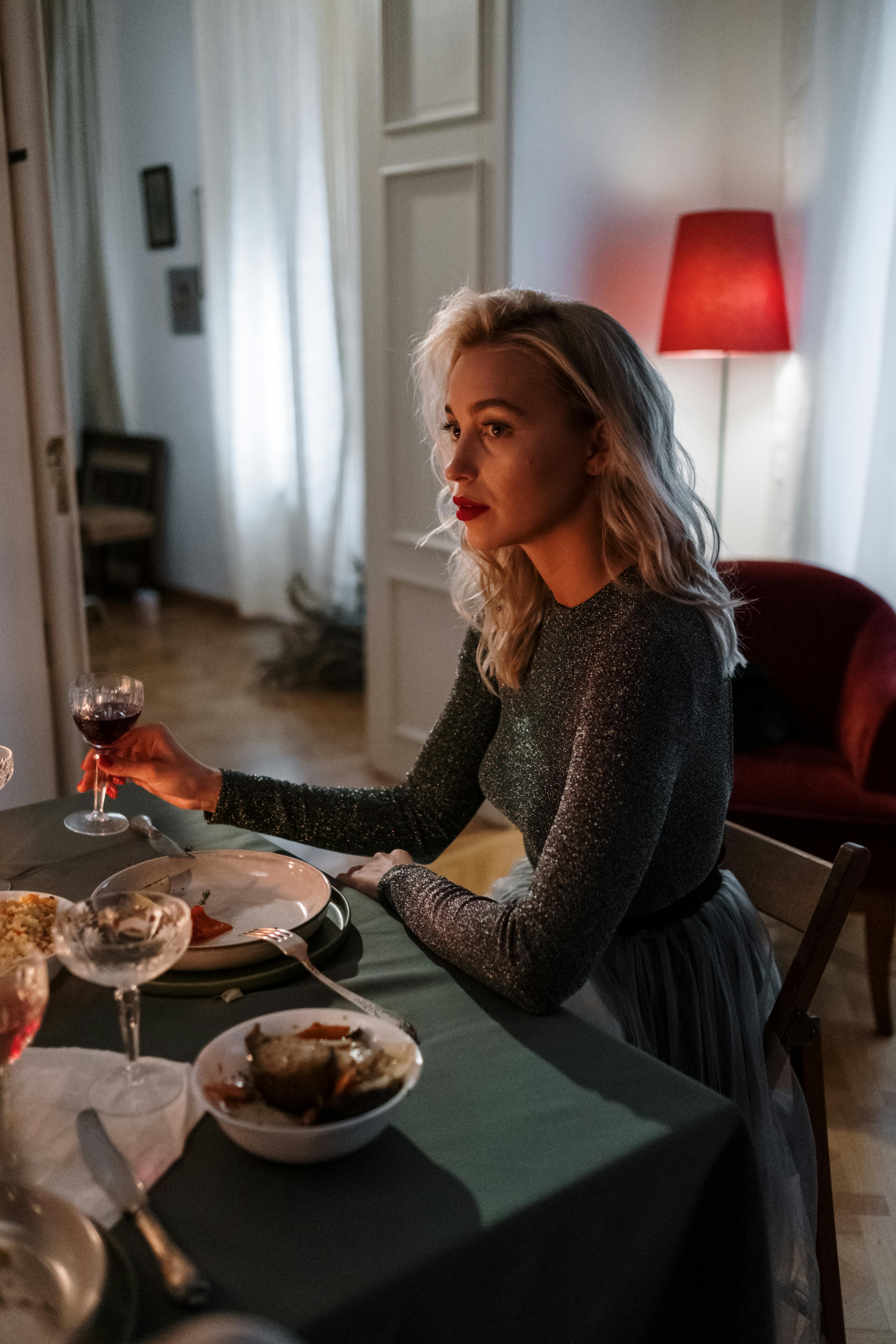 Frau hält ein Glas Wein während des Abendessens | Quelle: Pexels