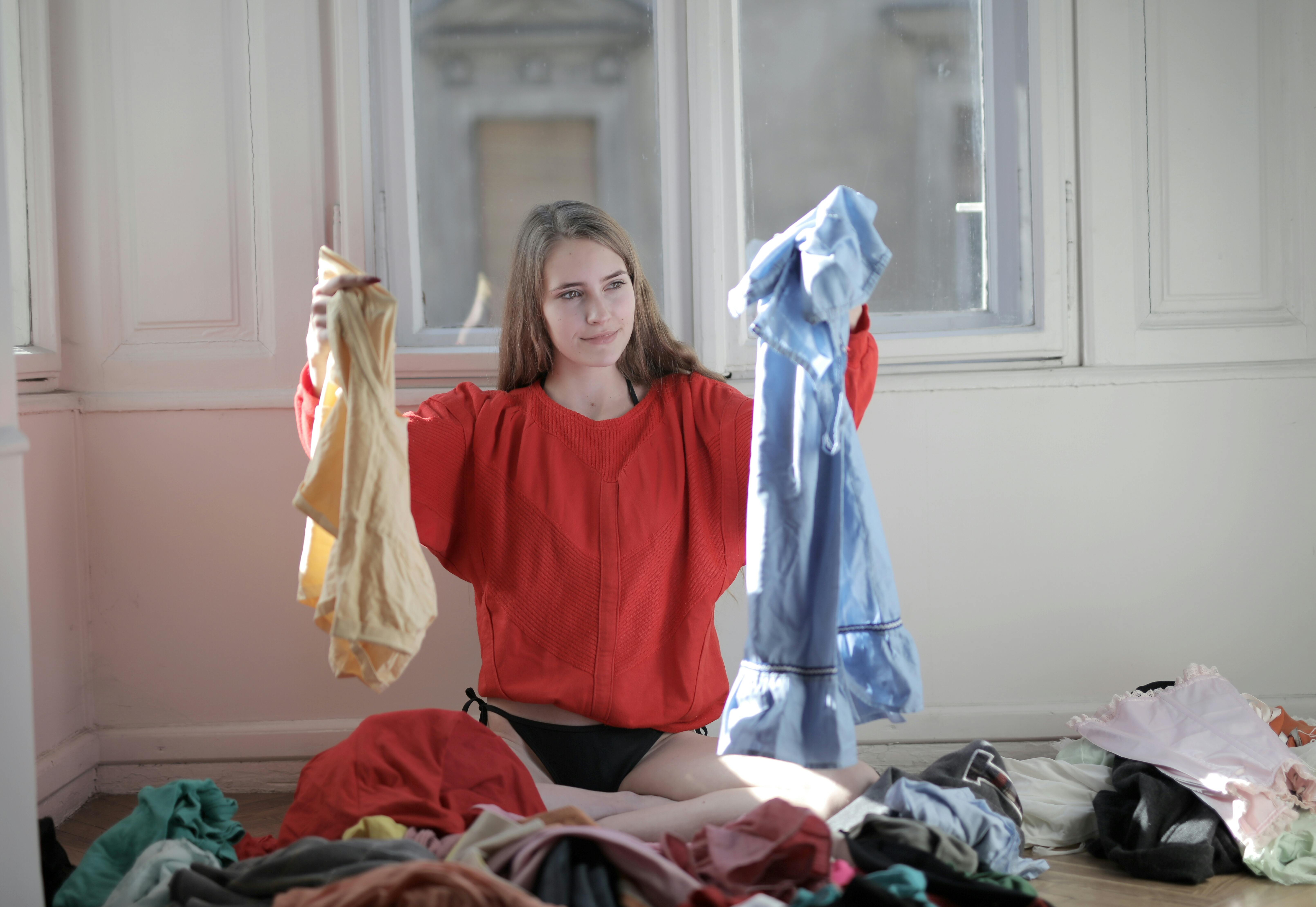 Frau hält Kleidungsstücke aus der Wäscherei hoch | Quelle: Pexels