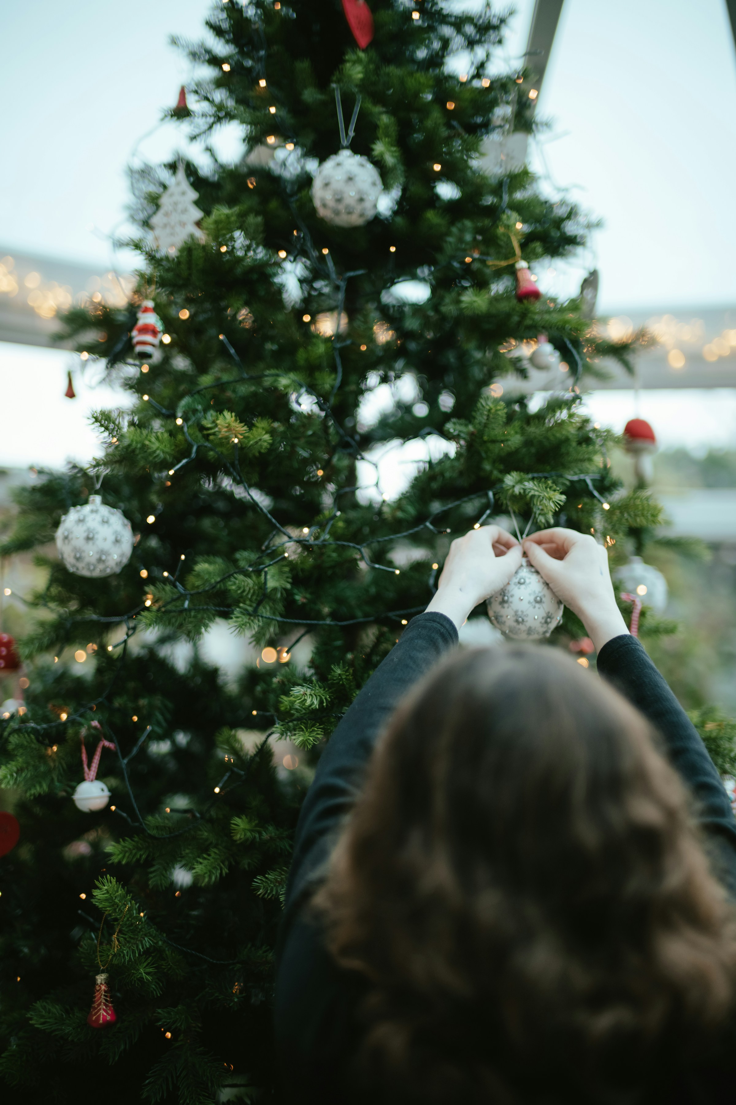 Eine Frau schmückt einen Weihnachtsbaum | Quelle: Unsplash