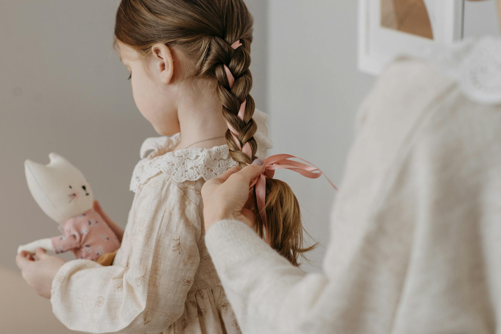 Eine Frau bindet ihrer Tochter eine Schleife ins Haar | Quelle: Pexels