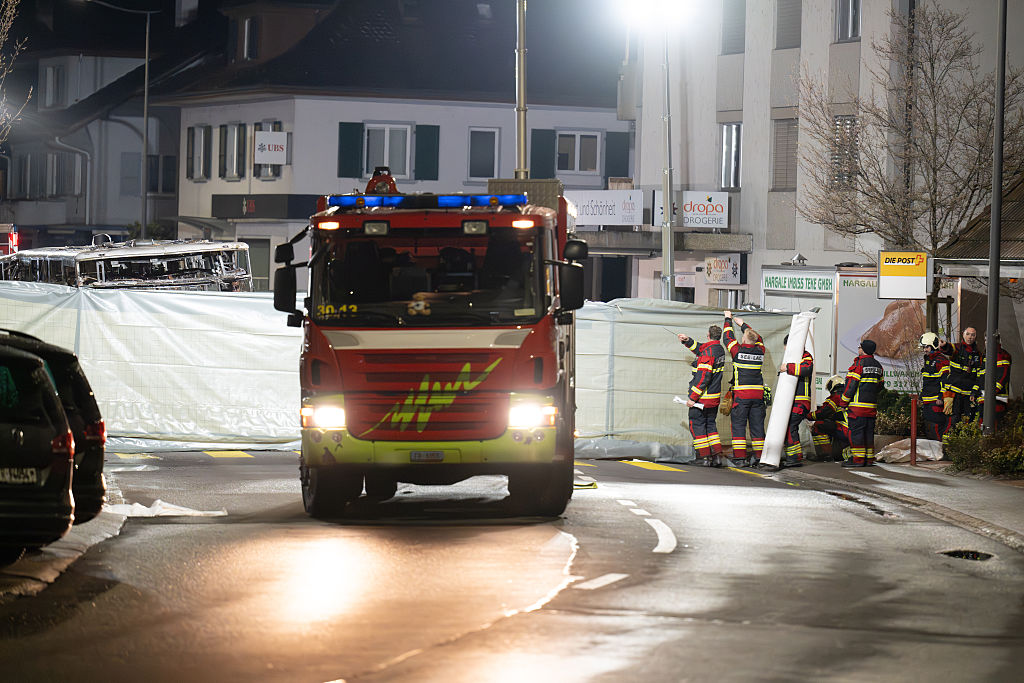 Feuerwehrleute arbeiten neben den Überresten des Busses, der am Abend des 10. März 2026 in Kerzers, Schweiz, in Brand geraten ist. | Quelle: Getty Images