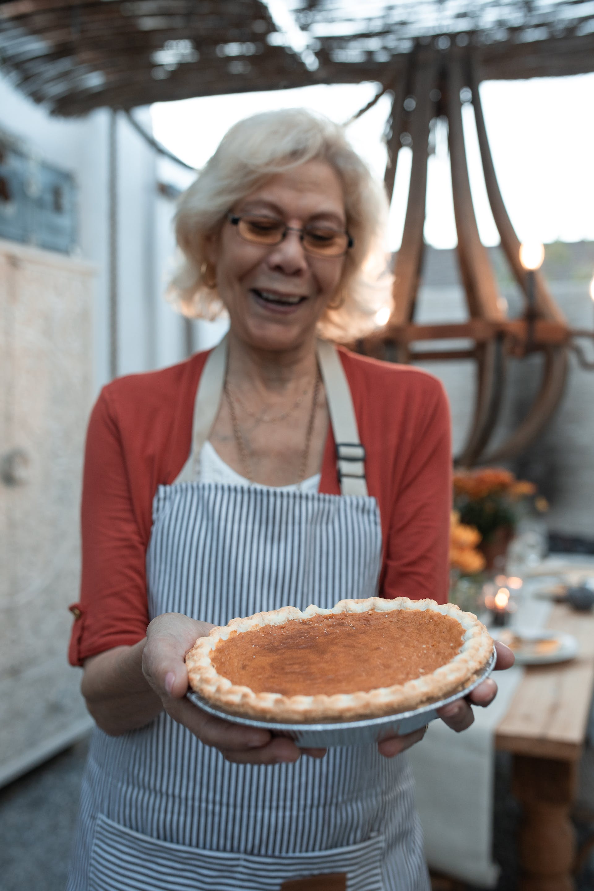 Eine lächelnde ältere Frau, die einen Kürbiskuchen hält | Quelle: Pexels