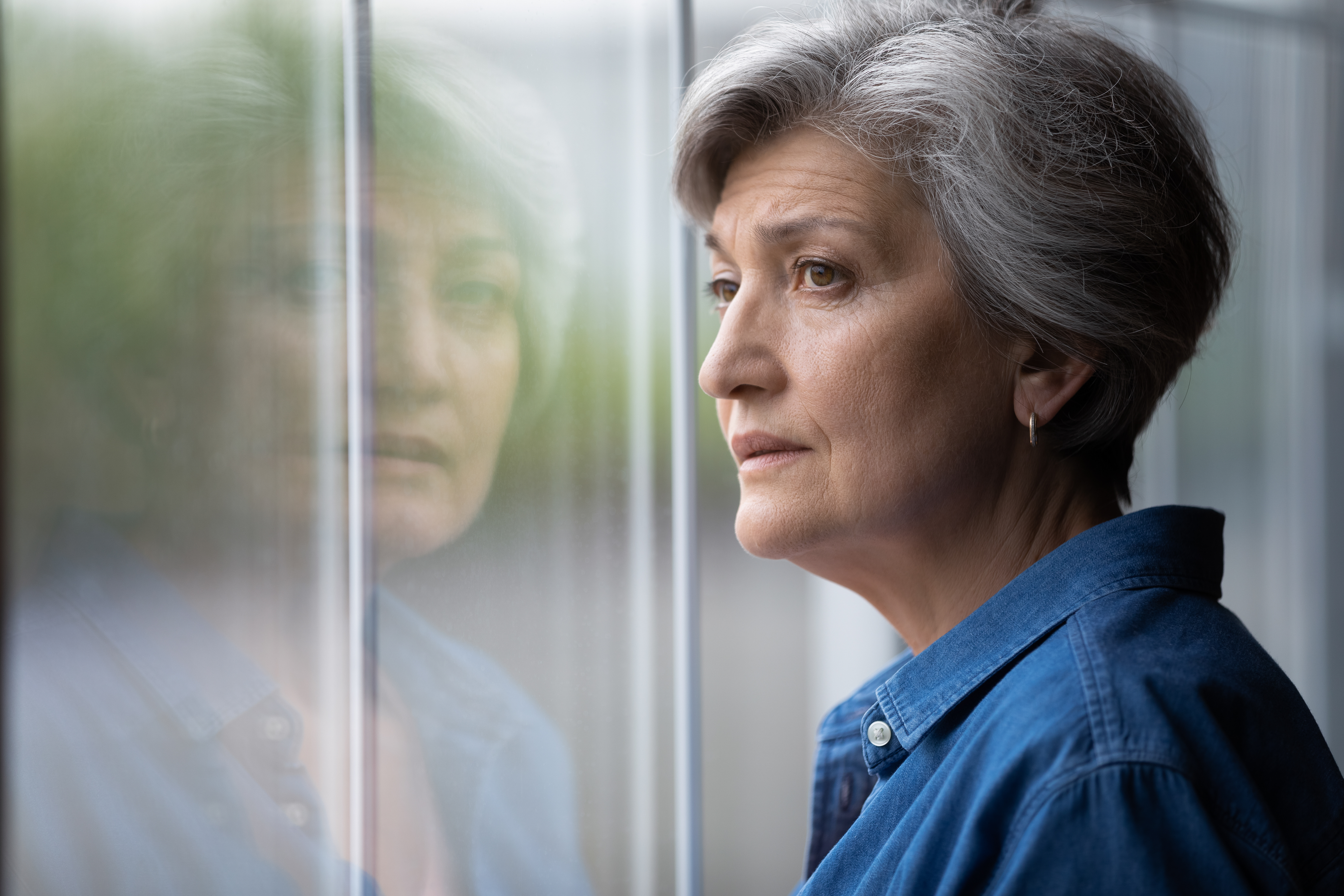 Eine ältere Frau, die an einem Fenster steht | Quelle: Shutterstock