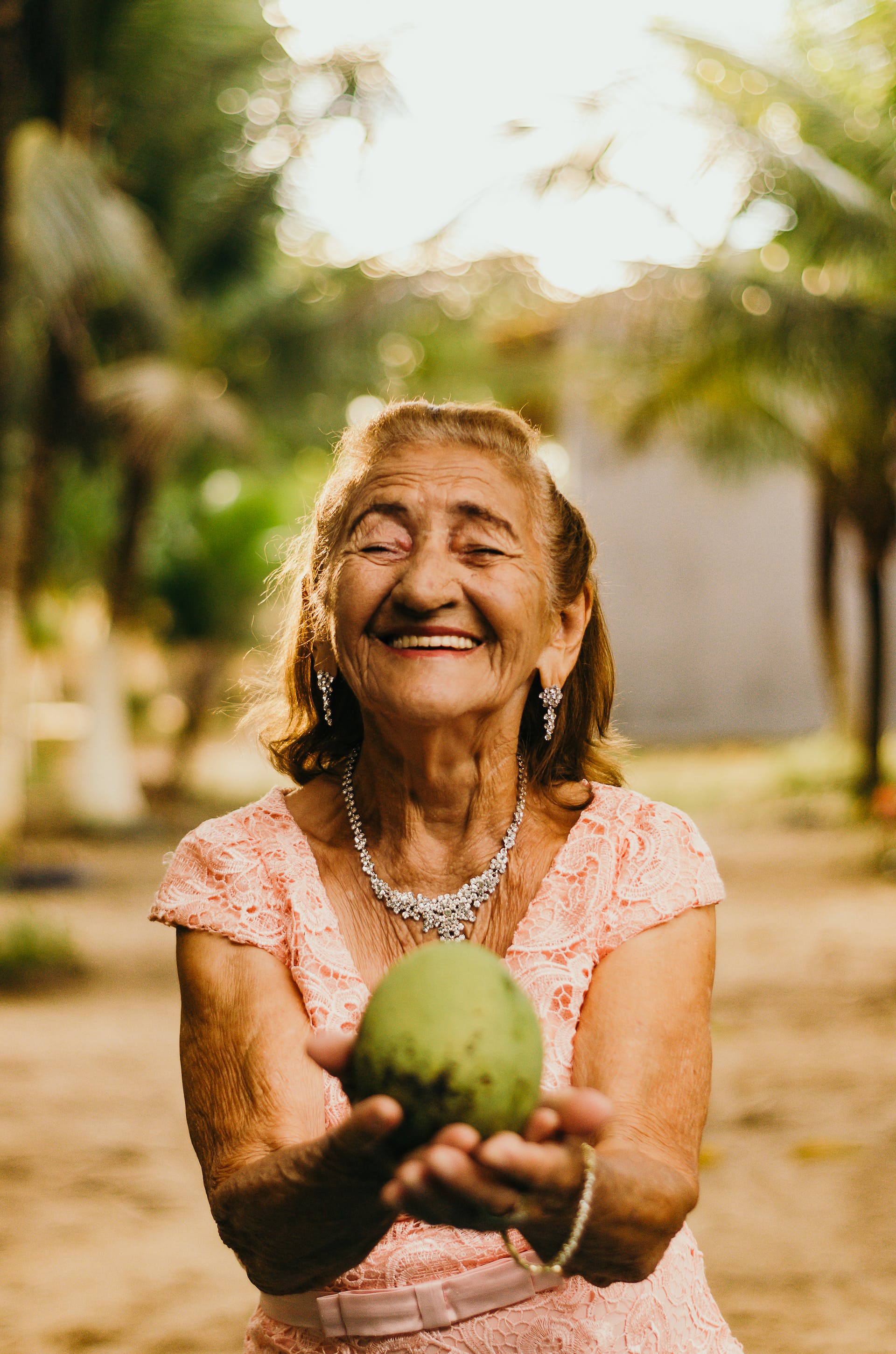 Alte Frau lächelt und hält eine Kokosnuss | Quelle: Pexels