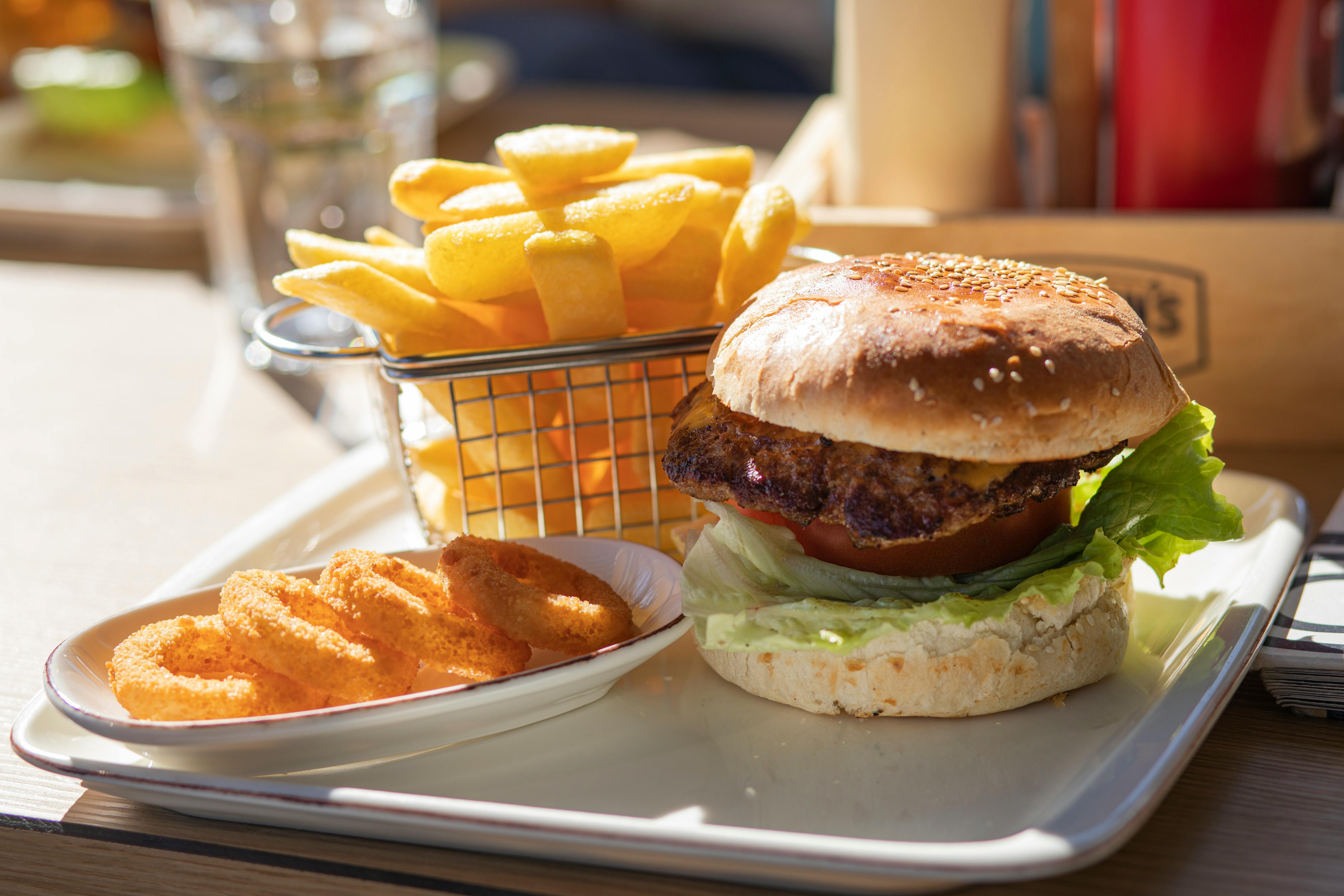 Ein Tablett mit Hamburgern, Pommes und Zwiebelringen | Quelle: Pexels