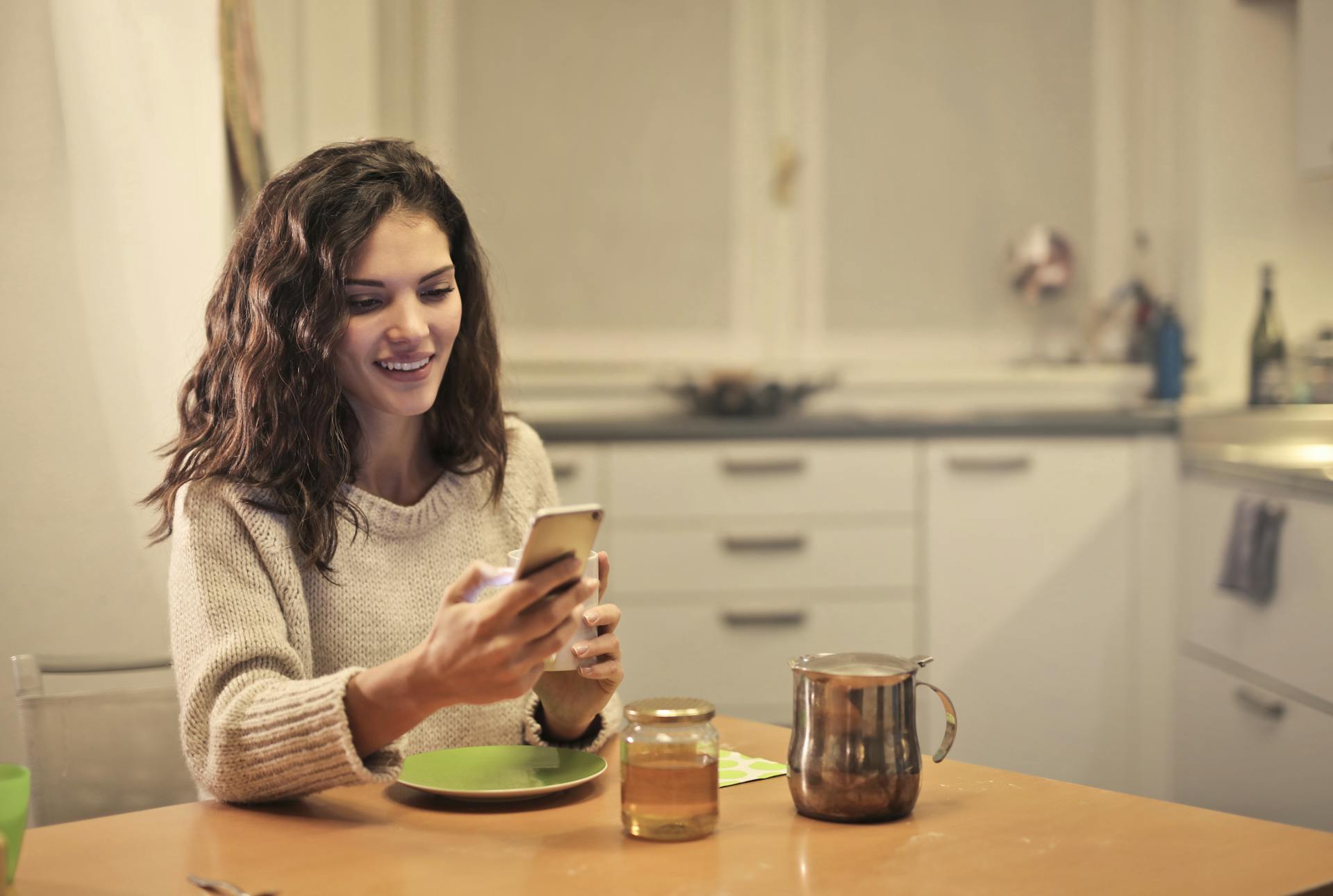 Eine junge Frau trinkt Tee und benutzt ihr Telefon | Quelle: Pexels