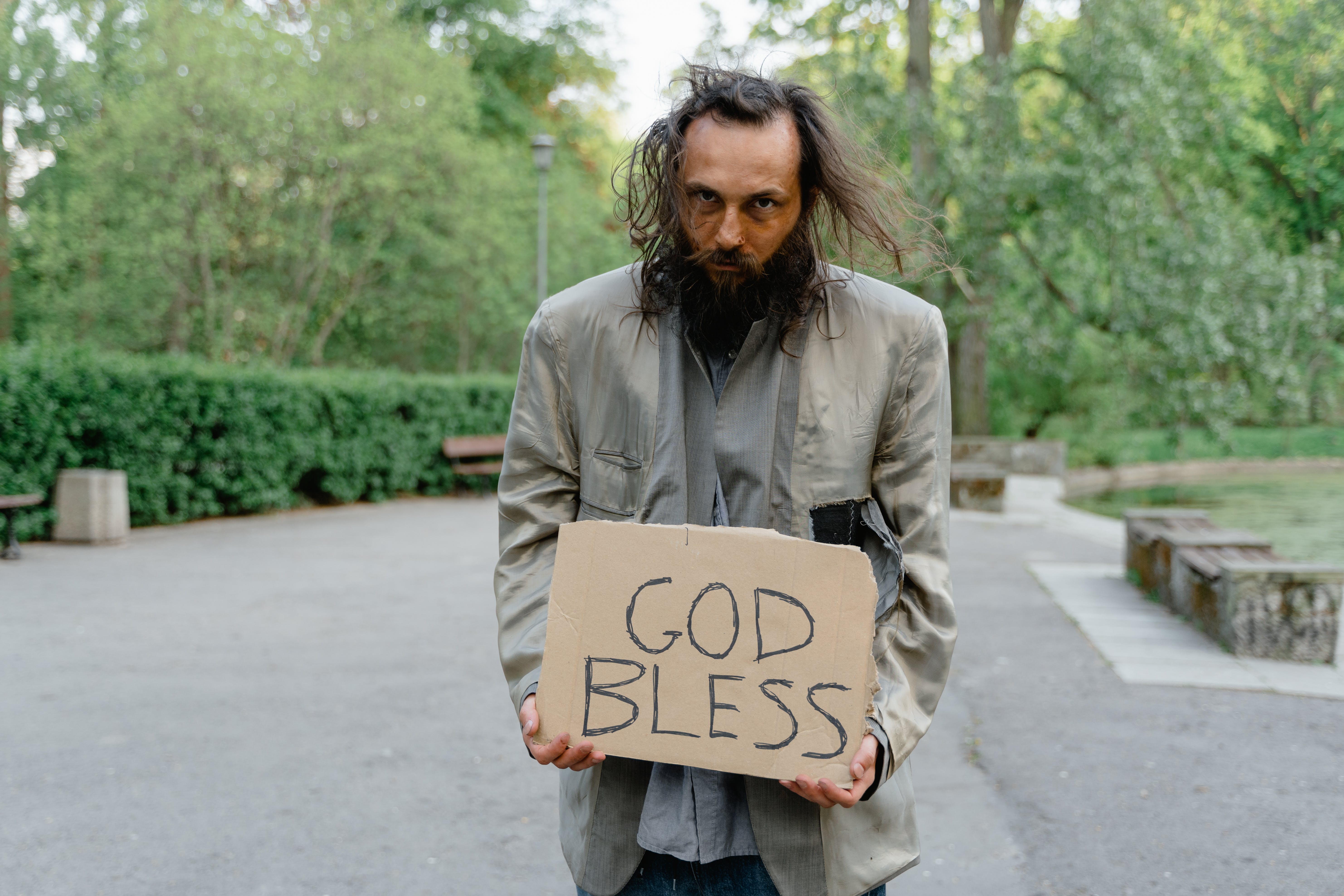 Ein obdachloser Mann steht mit einem Schild auf der Straße | Quelle: Pexels