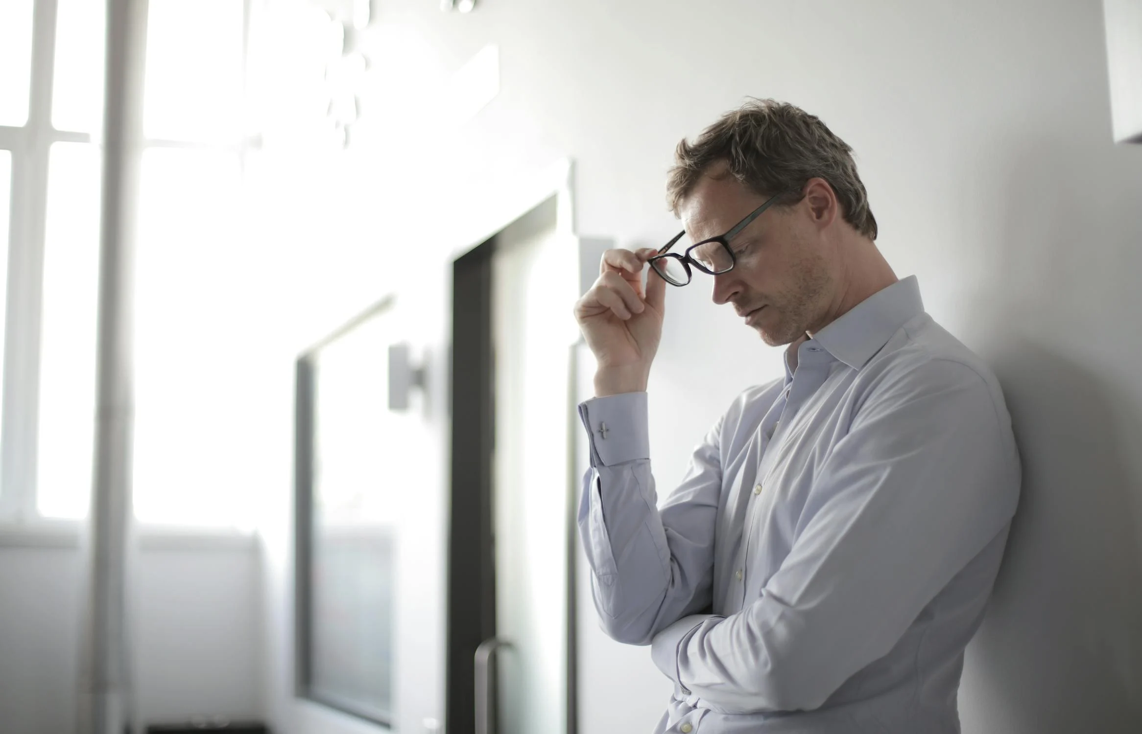 Ein müder Mann nimmt seine Brille ab | Quelle: Pexels