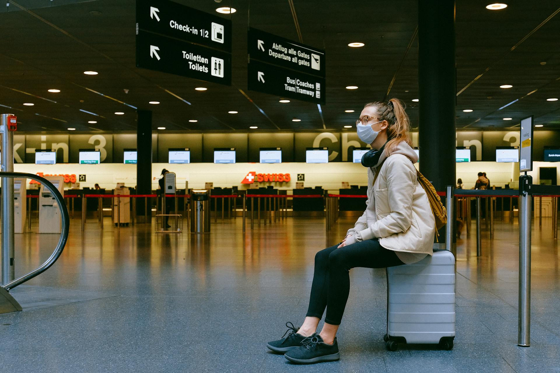 Frau, die auf einem Koffer an einem Flughafen sitzt | Quelle: Pexels