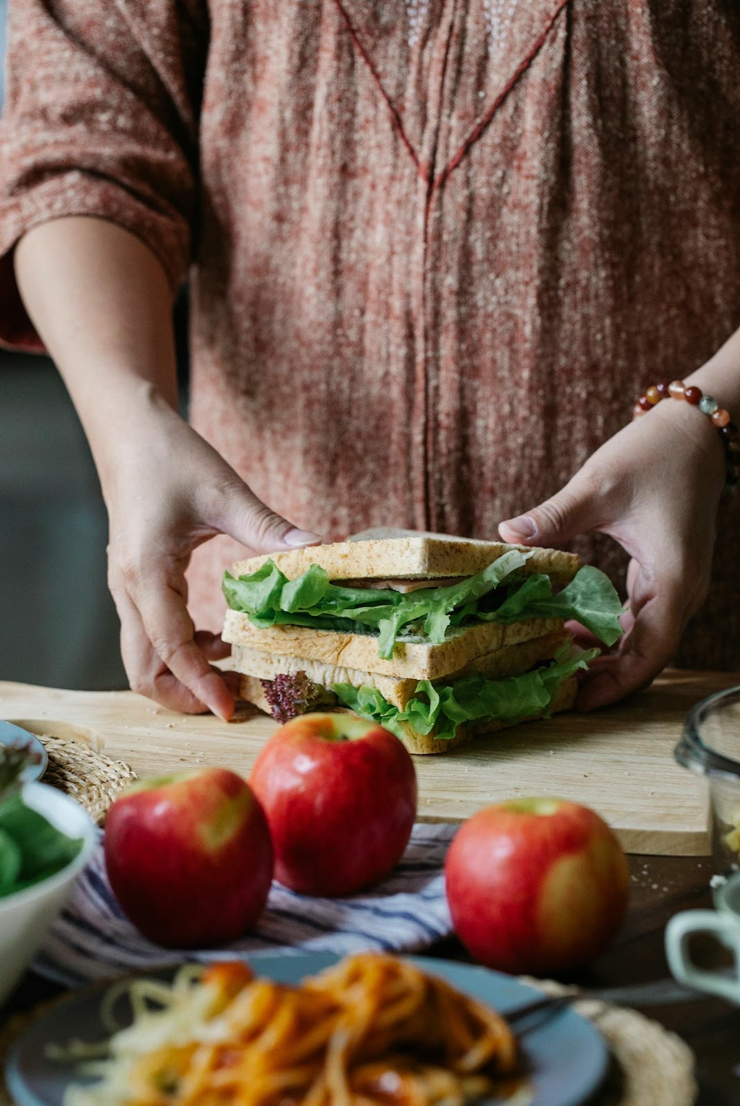 Eine Nahaufnahme einer Frau, die ein Sandwich zubereitet | Quelle: Pexels