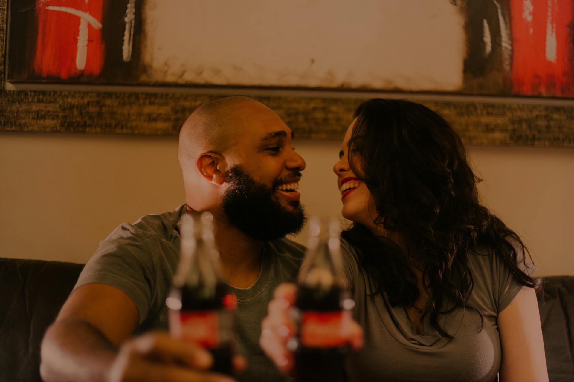 Ein Paar lacht, während es seine Softdrinkflaschen hält | Quelle: Pexels