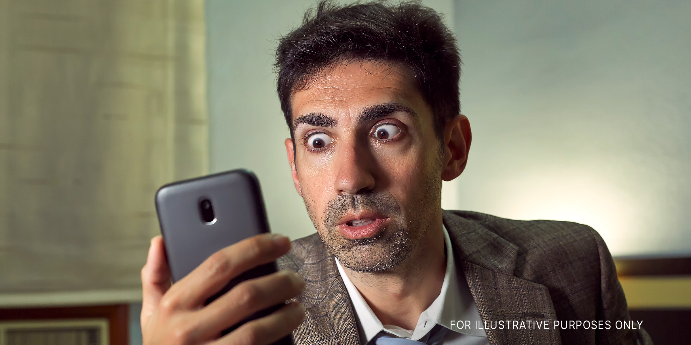 Ein Mann, der mit großen Augen auf sein Telefon schaut | Quelle: Shutterstock
