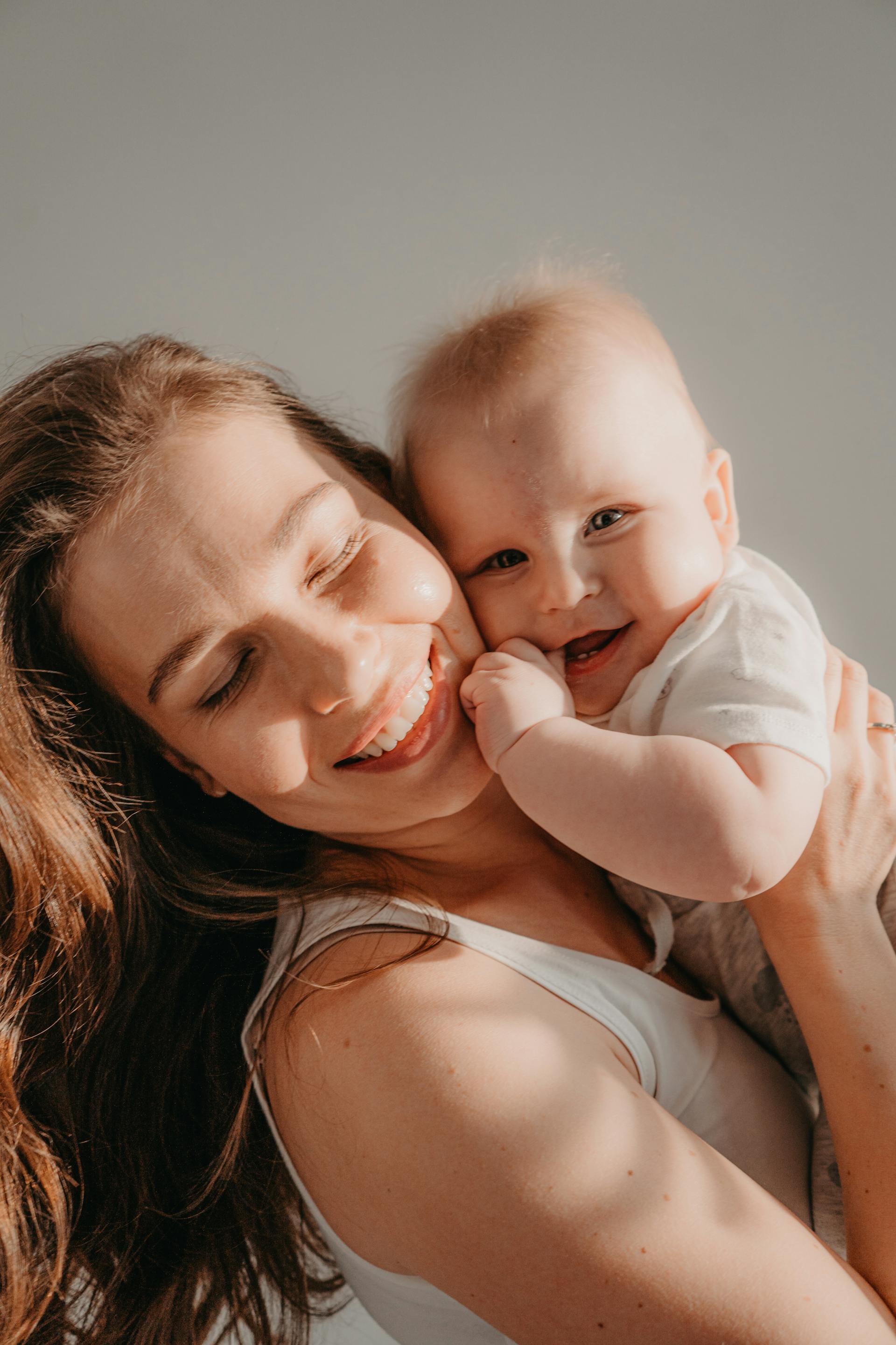 Eine glückliche Frau, die ein lächelndes Baby hält | Quelle: Pexels