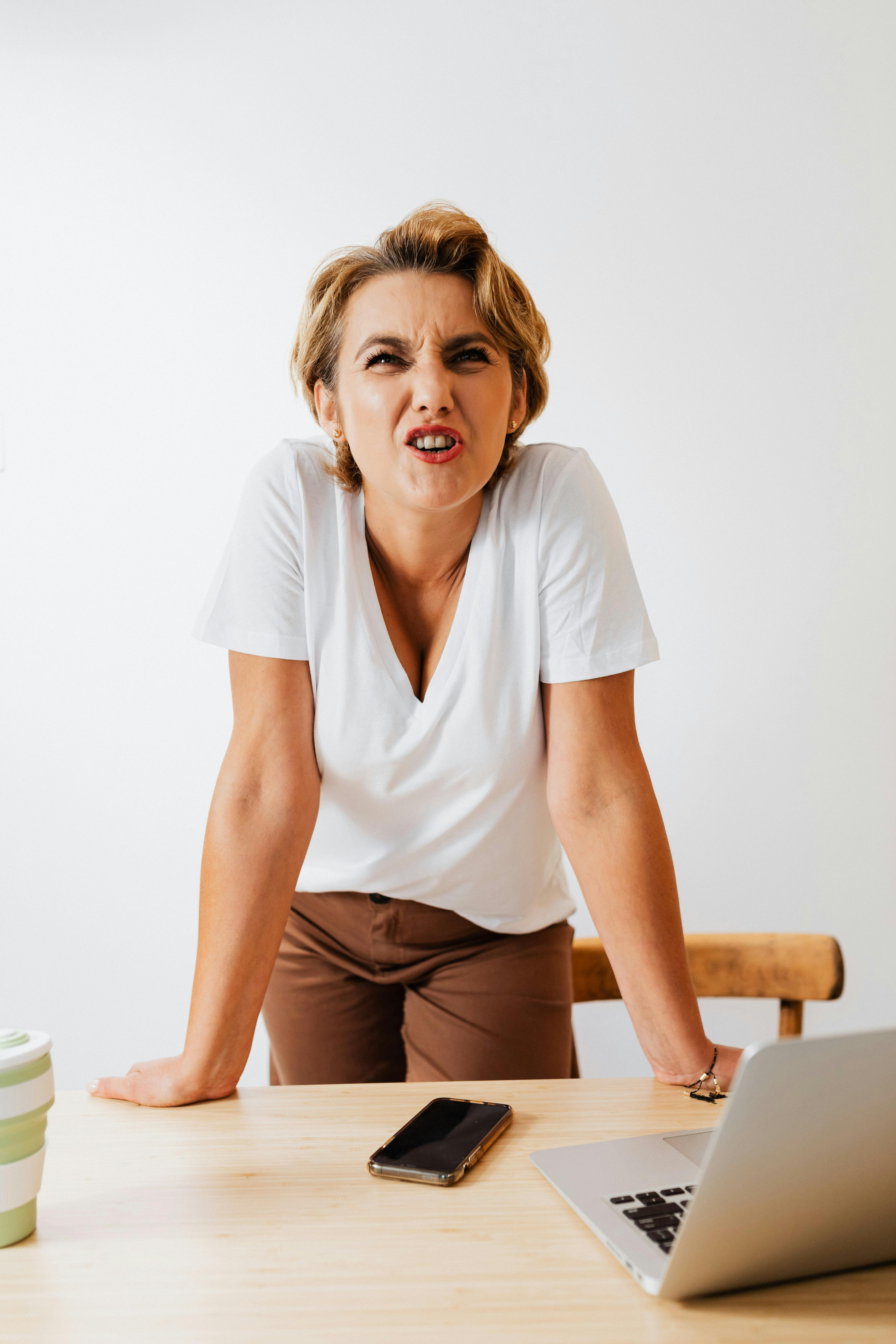 Eine Frau, die wütend reagiert, während sie ihre Hände auf einem Tisch balanciert | Quelle: Pexels