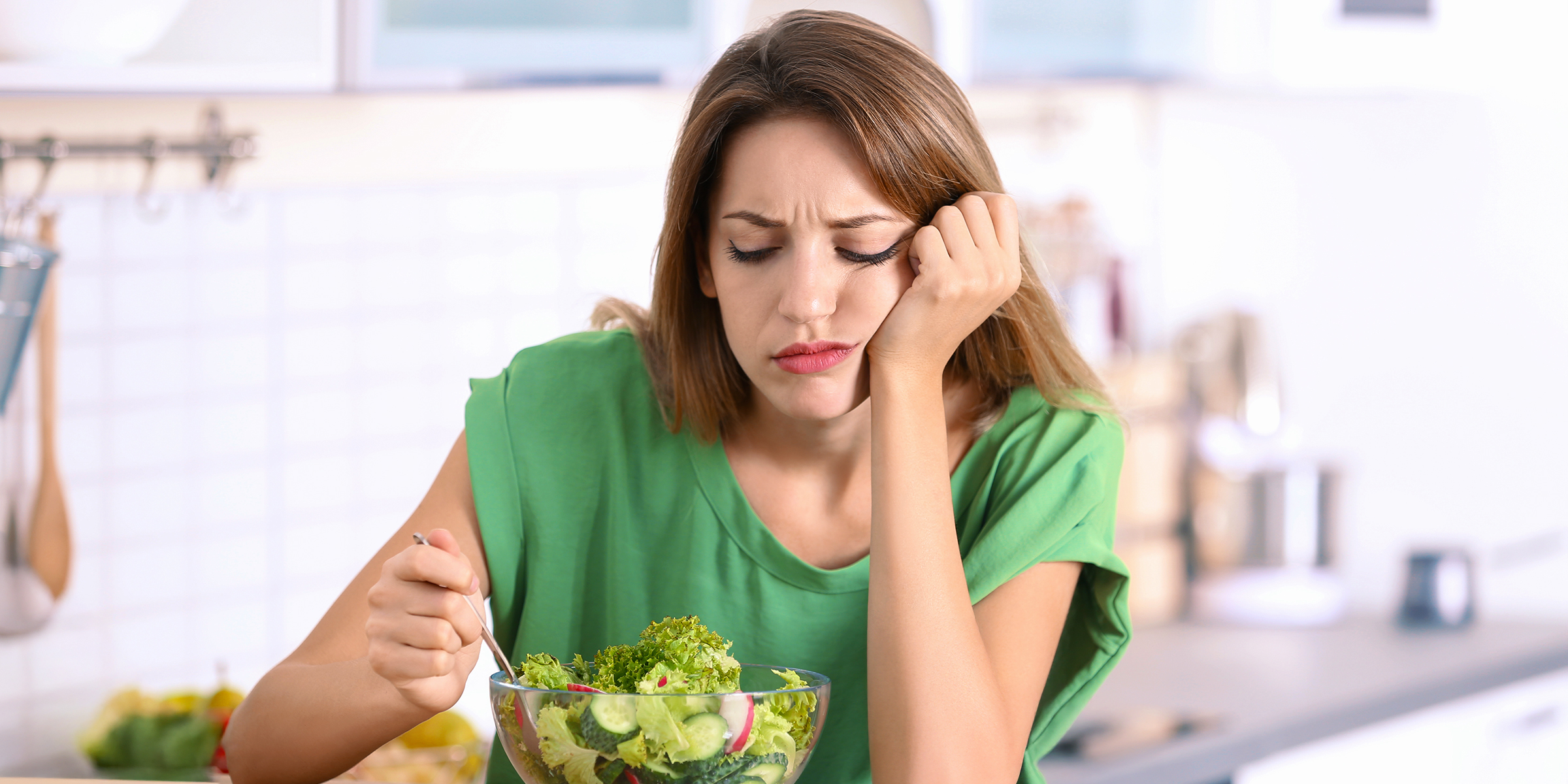 Eine gelangweilte Frau schaut auf ihren Salat | Quelle: Shutterstock