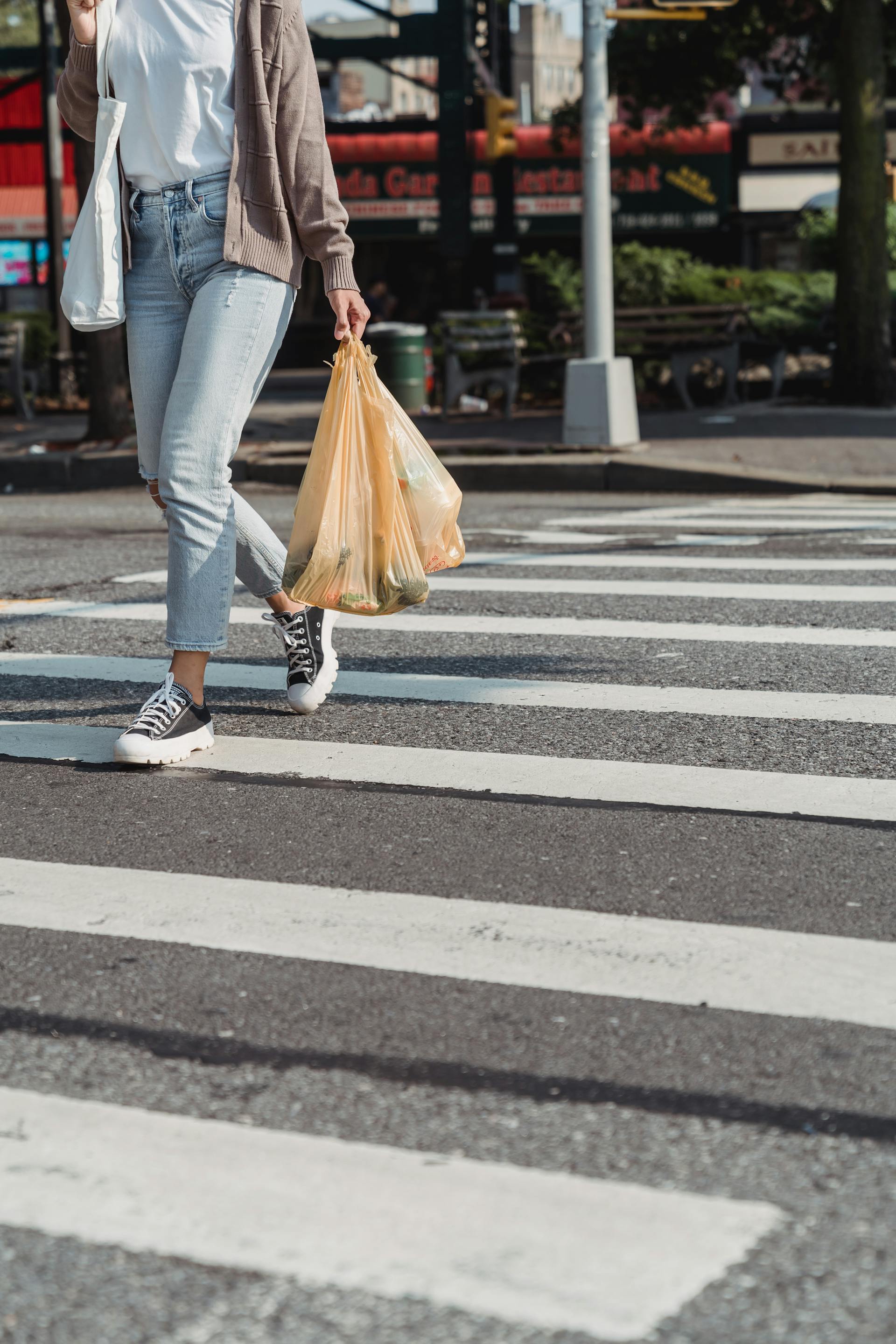 Eine Frau, die mit Einkaufstüten in der Hand über einen Zebrastreifen geht | Quelle: Pexels