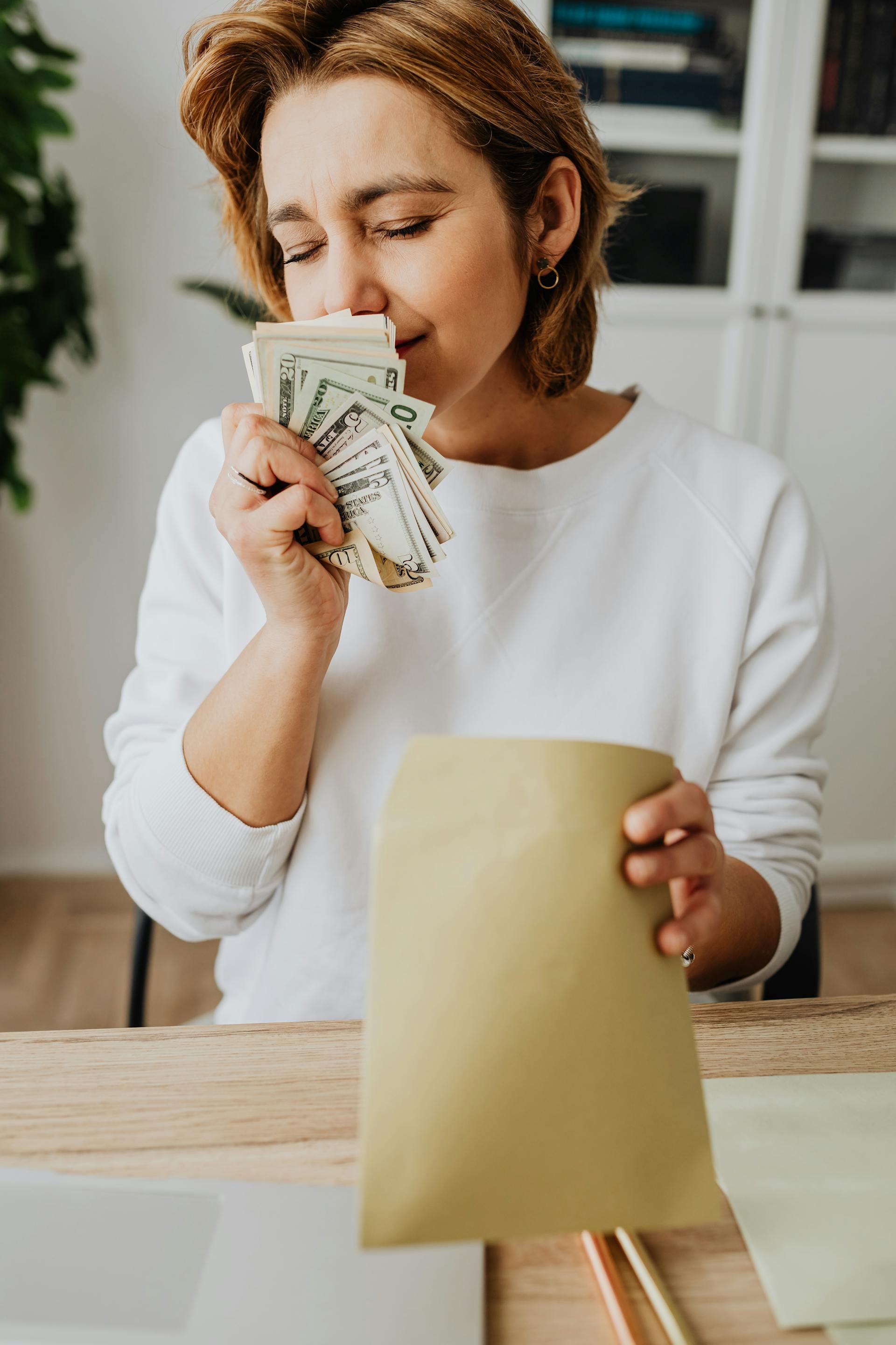 Eine Frau, die mit geschlossenen Augen an Geld riecht | Quelle: Pexels