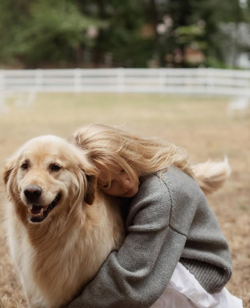 Pamela Anderson vergräbt ihr Gesicht im weichen Fell ihres Golden Retrievers, während sie einen ruhigen Moment im Freien auf ihrem Anwesen in Arcady genießt. Warm angezogen in einen grob gestrickten grauen Pullover und einen wallenden weißen Rock, vor dem Hintergrund von Bäumen und weißen Weidezäunen, genießt sie eine zärtliche Umarmung, die ihre tiefe Verbundenheit mit Tieren und die wohltuende Einfachheit ihres Zuhauses auf Vancouver Island unterstreicht. Sie hat das herzerwärmende Foto zusammen mit der Bildunterschrift „Wahre Liebe endet nie… 🤍“ gepostet. | Quelle: Instagram/pamelaanderson