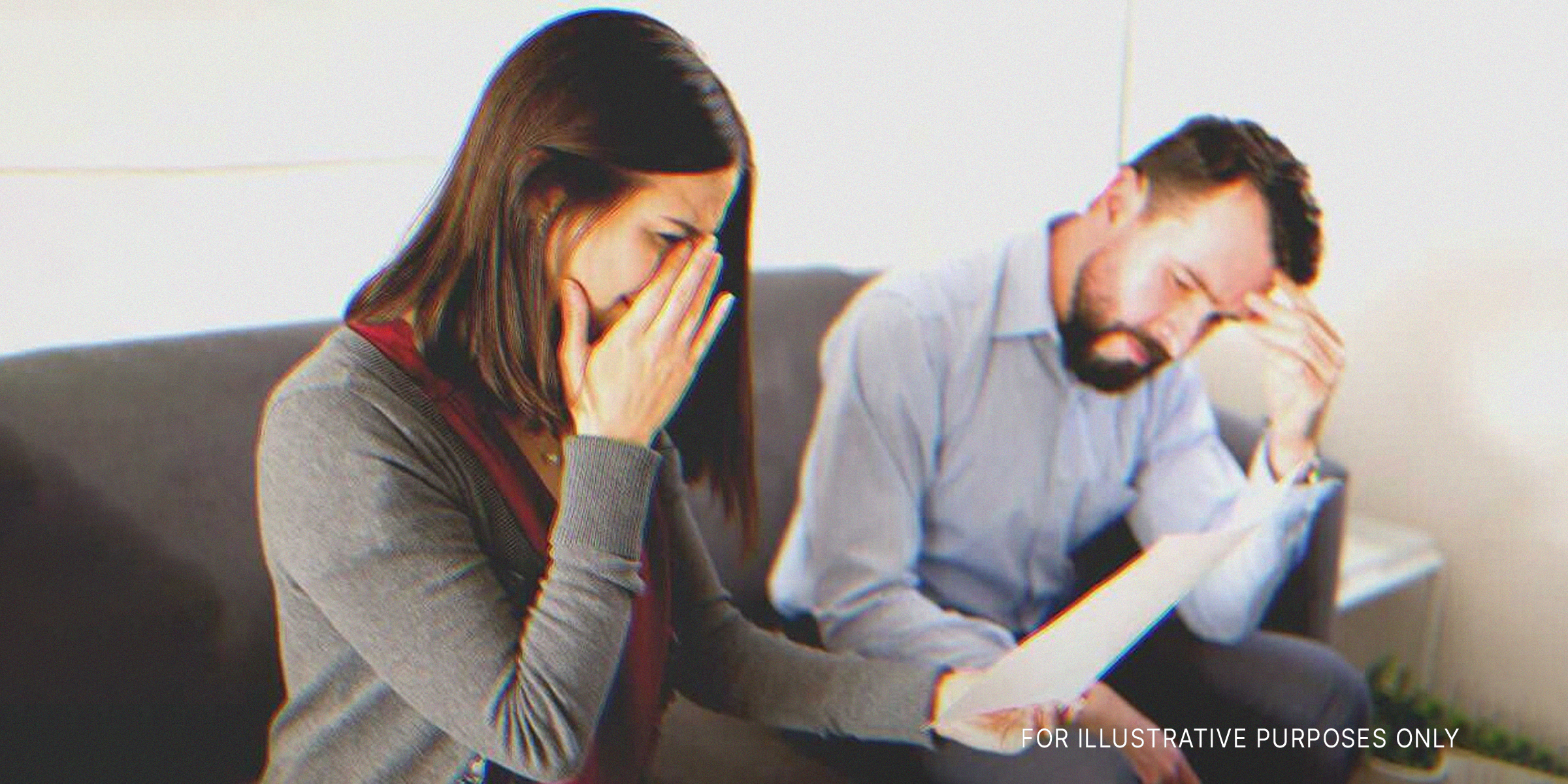 Eine weinende Frau mit einem Stück Papier in der Hand und einem Mann, der neben ihr sitzt | Quelle: Shutterstock