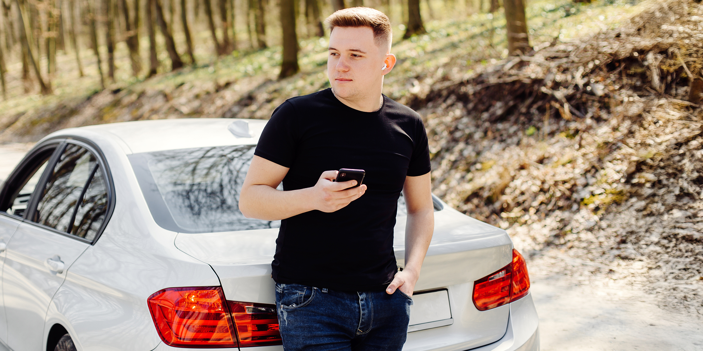 Ein Mann, der neben einem Auto steht und ein Telefon hält | Quelle: Shutterstock