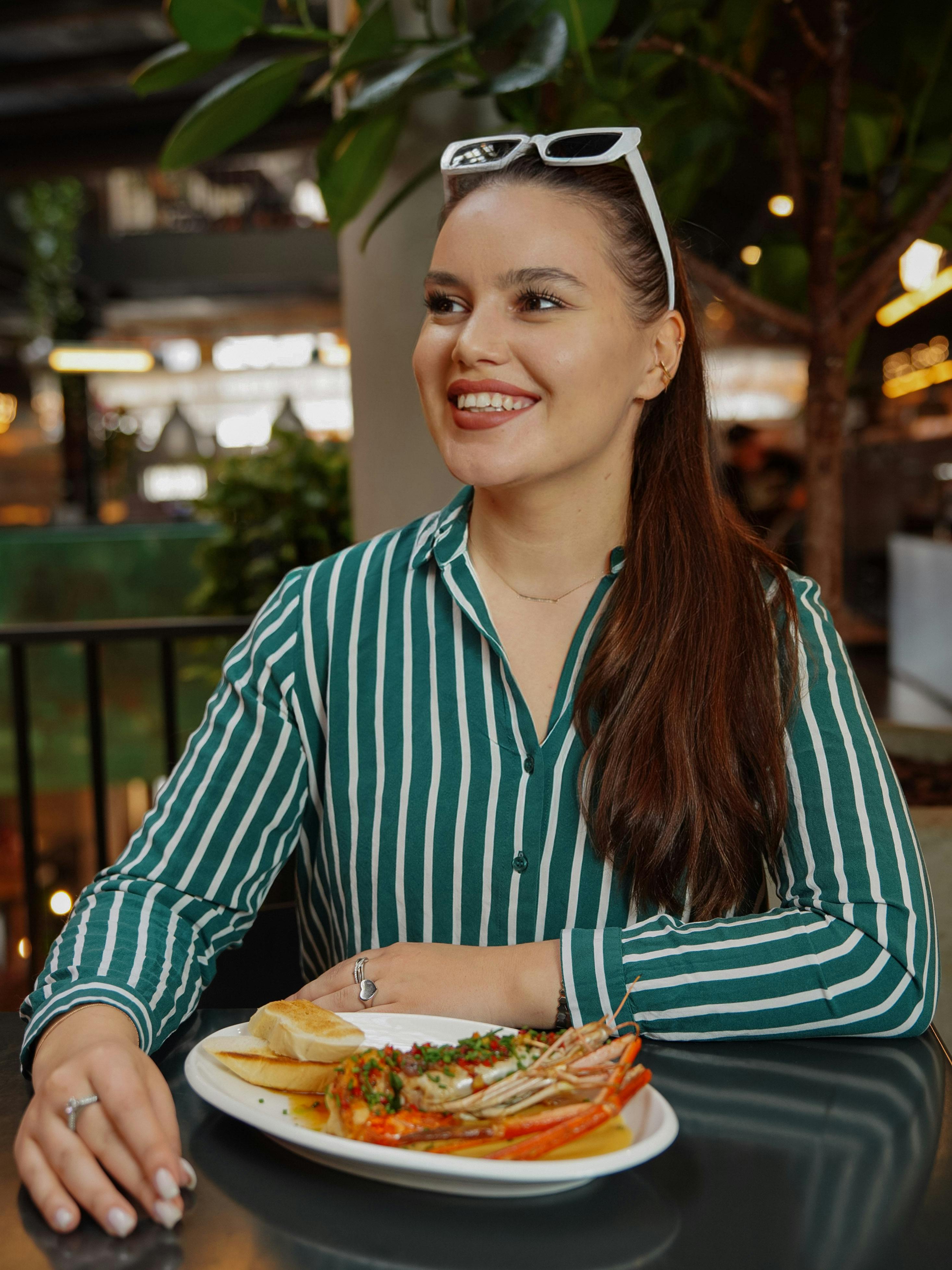 Eine glückliche junge Frau isst ein Hummergericht | Quelle: Pexels