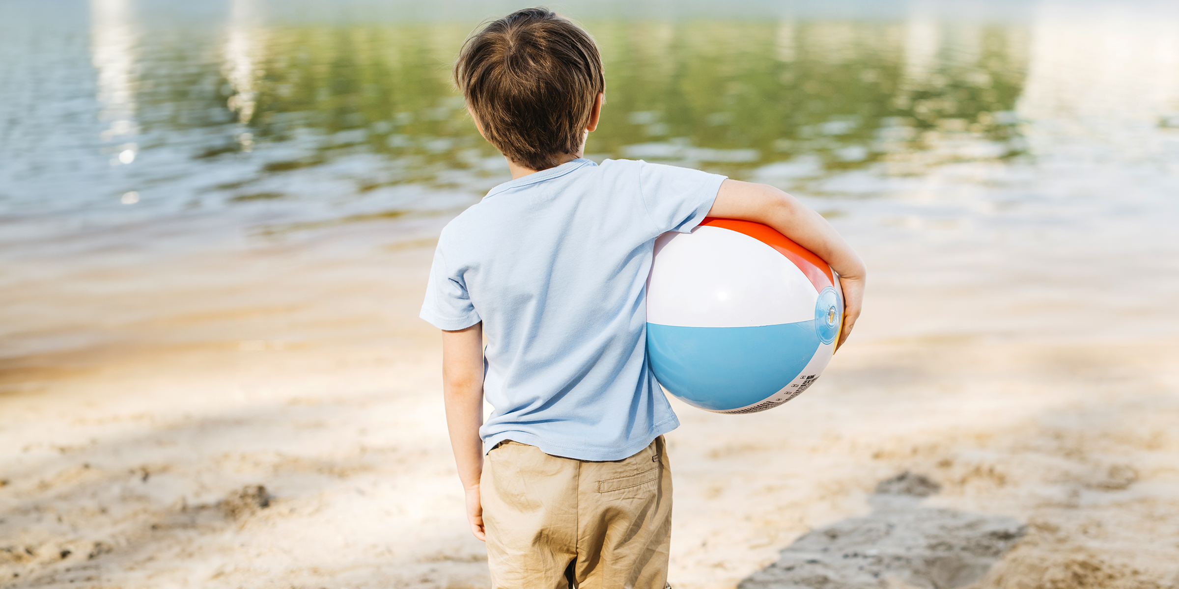 Ein kleiner Junge hält einen Ball am Strand | Quelle: Freepik