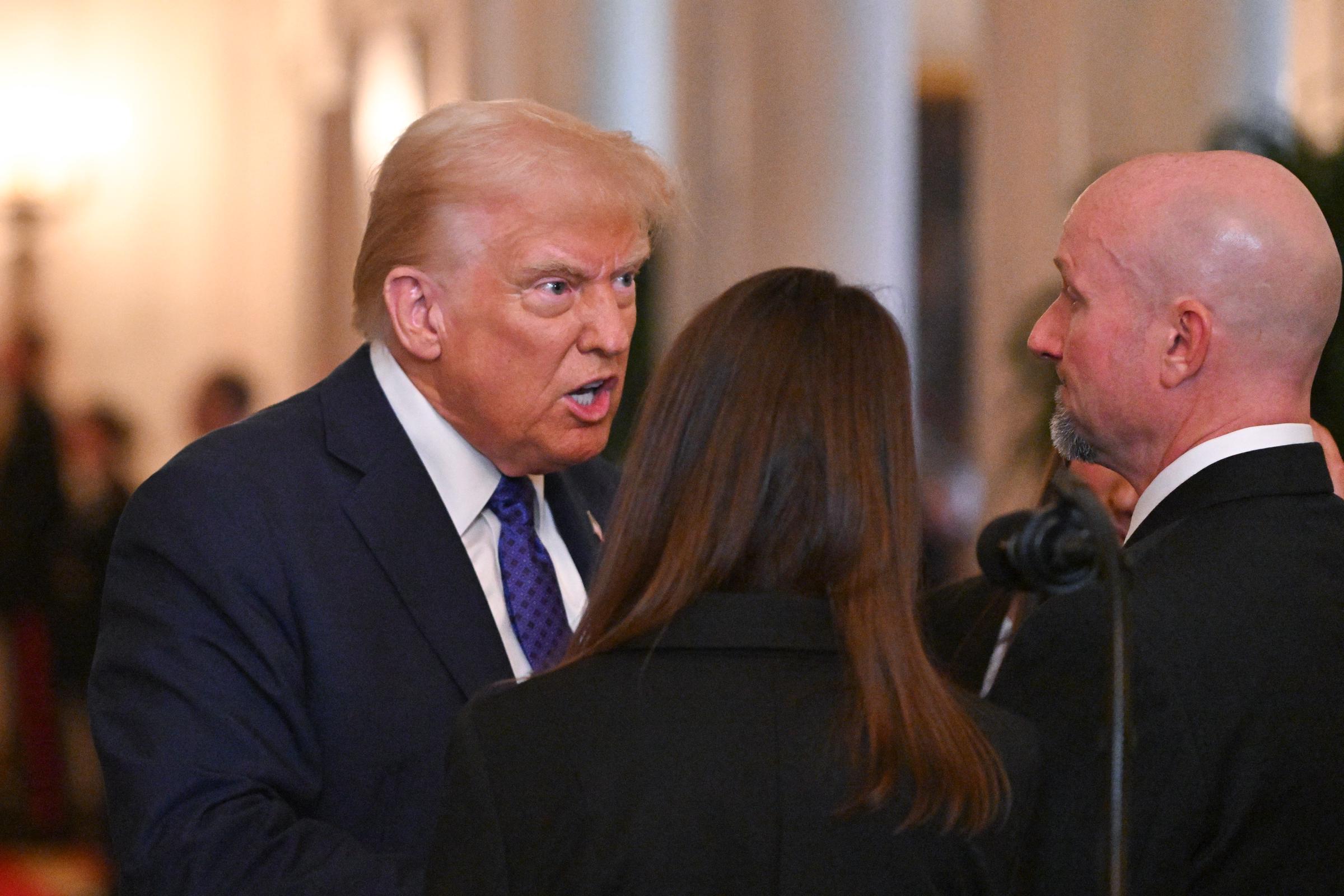 US-Präsident Donald Trump spricht mit Allyson Phillips, der Mutter von Laken Riley, und John Phillips, dem Stiefvater von Laken Riley, bevor er den Laken Riley Act im East Room des Weißen Hauses in Washington, D.C., unterzeichnet, 29. Januar 2025. | Quelle: Getty Images