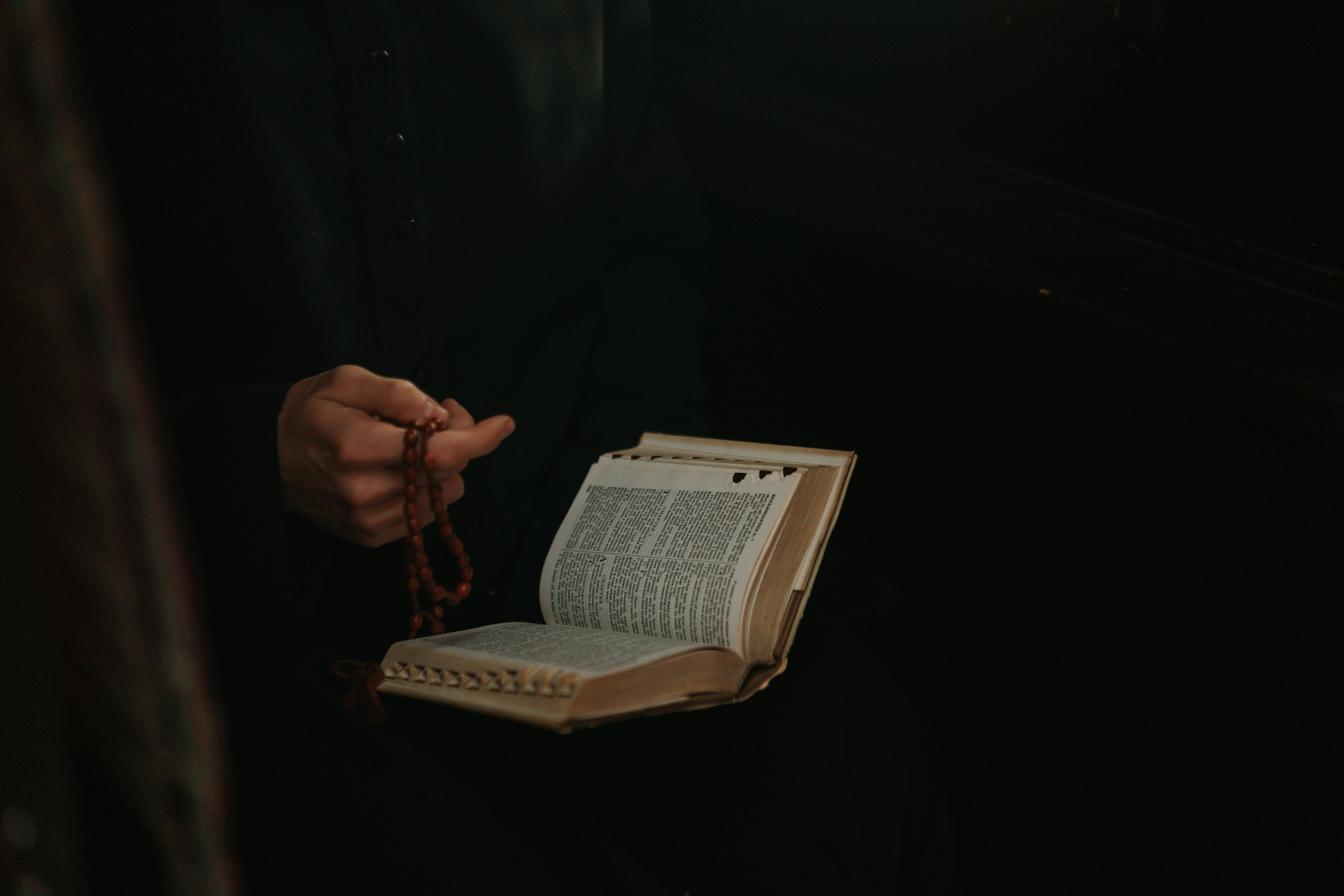 Ein Pastor hält einen Rosenkranz und eine Bibel in der Hand | Quelle: Pexels
