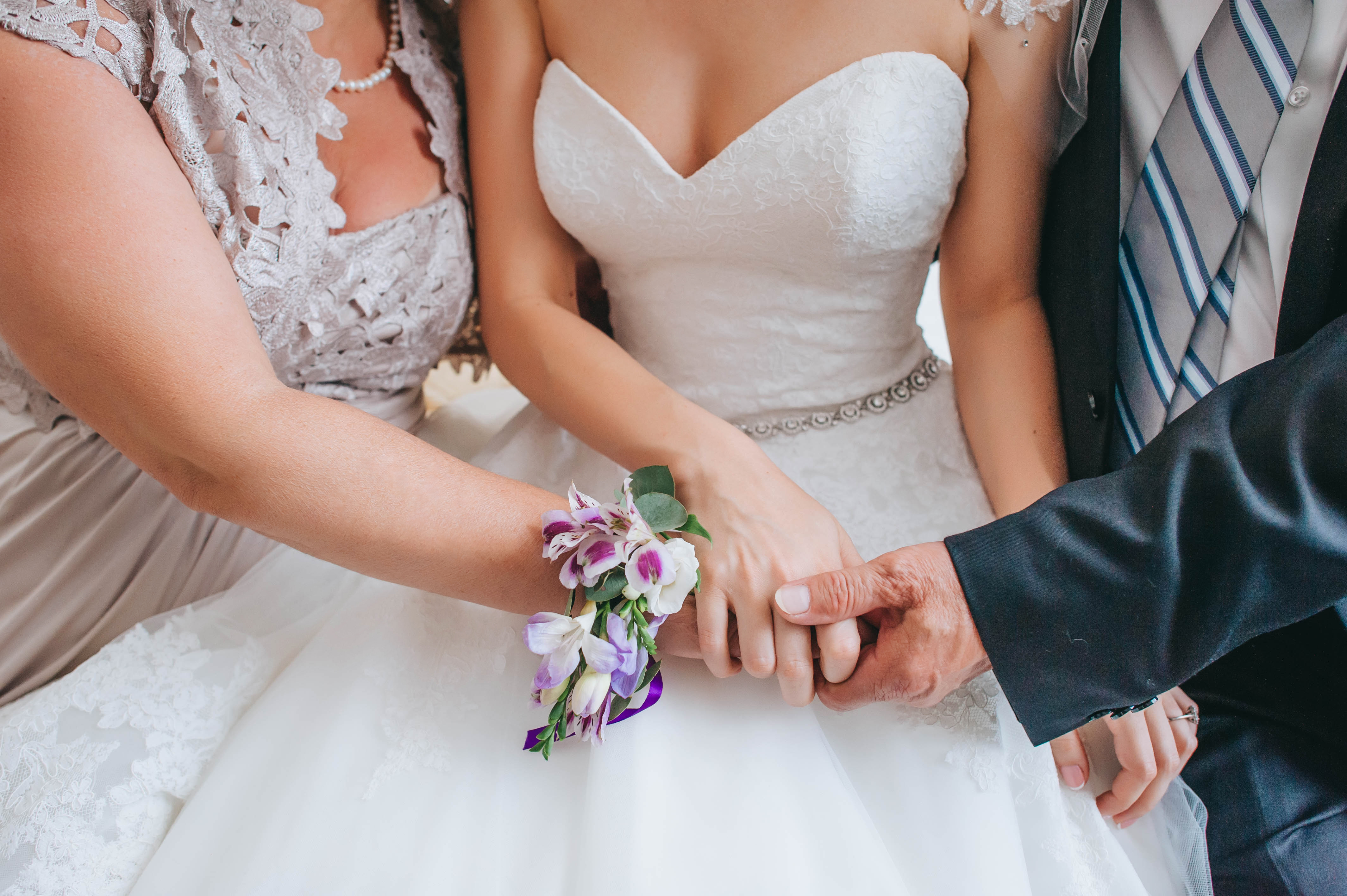 Eltern halten die Hand ihrer Tochter an deren Hochzeitstag | Quelle: Shutterstock