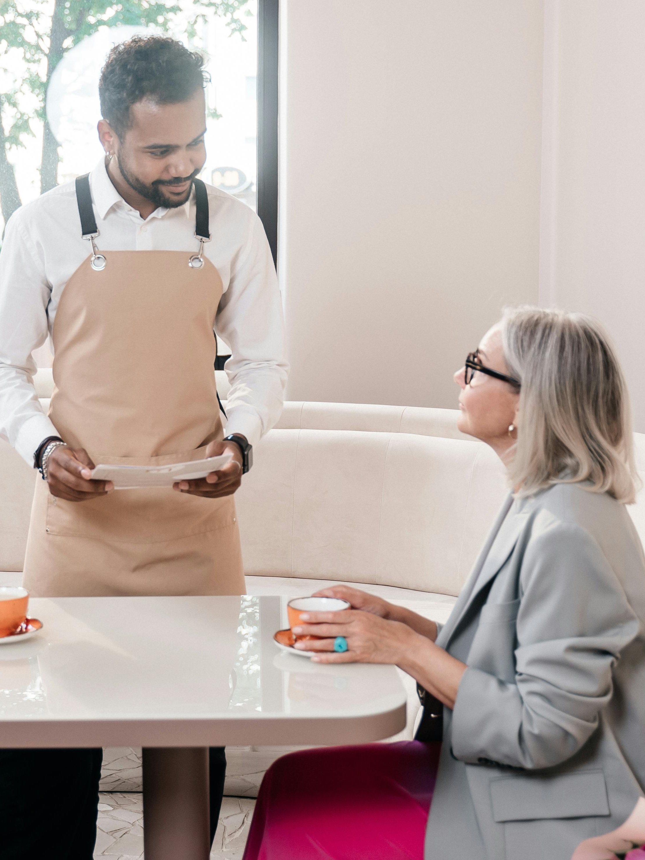 Ein Kellner bespricht etwas mit einem Restaurantgast | Quelle: Pexels