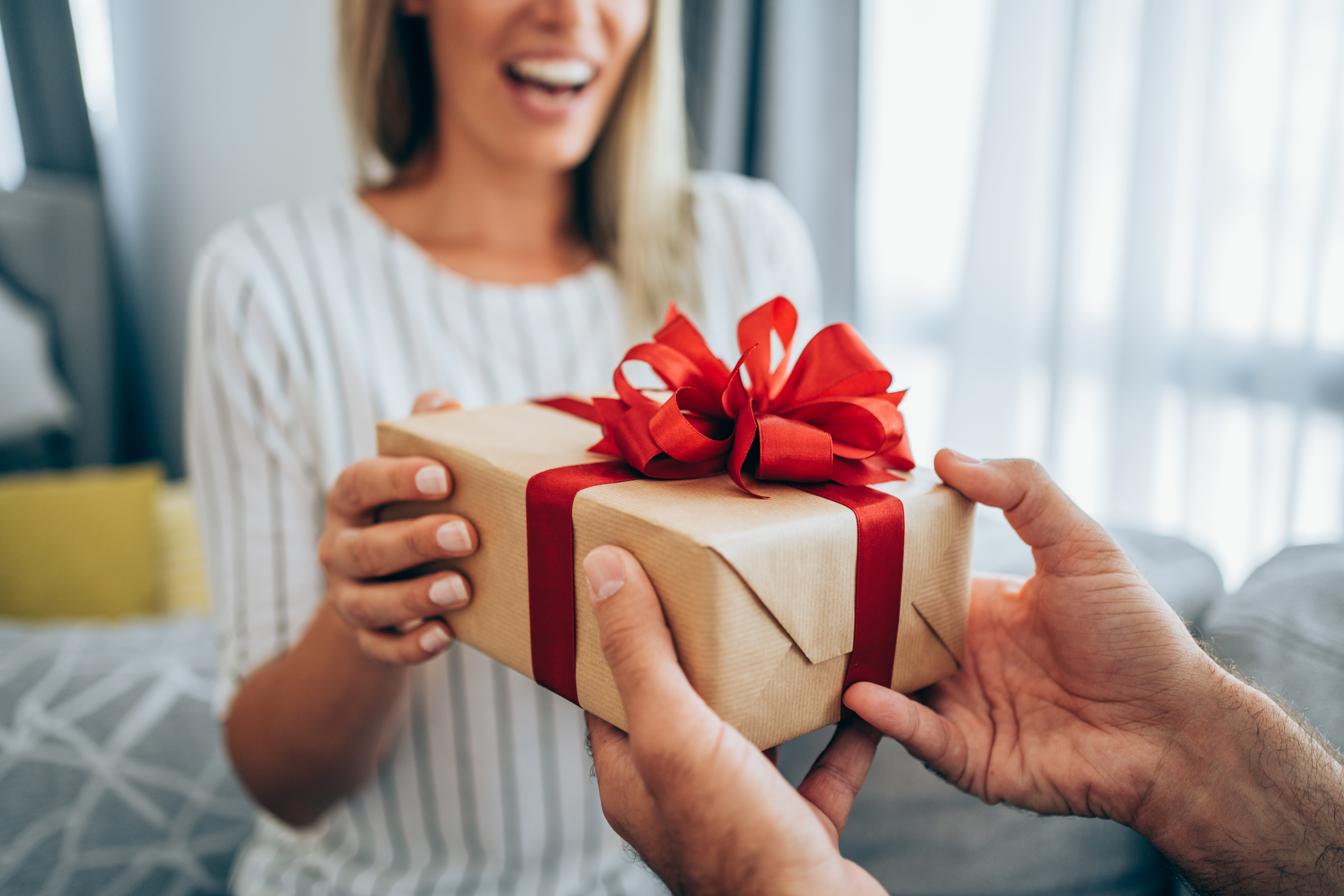 Eine glückliche Frau erhält ein Geschenk von einem Mann | Quelle: Getty Images