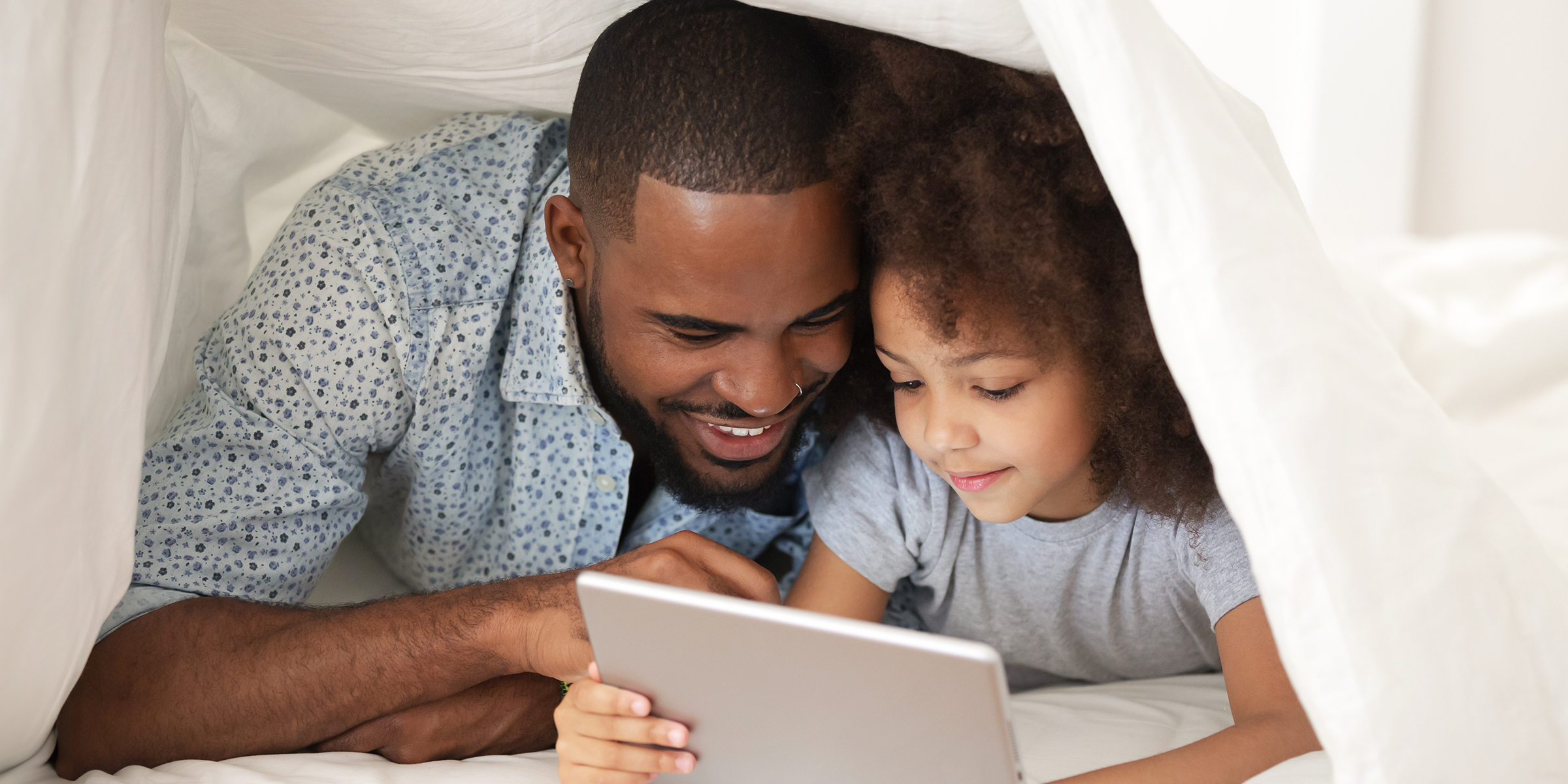 Ein Vater-Tochter-Duo nutzt ein Tablet | Quelle: Shutterstock