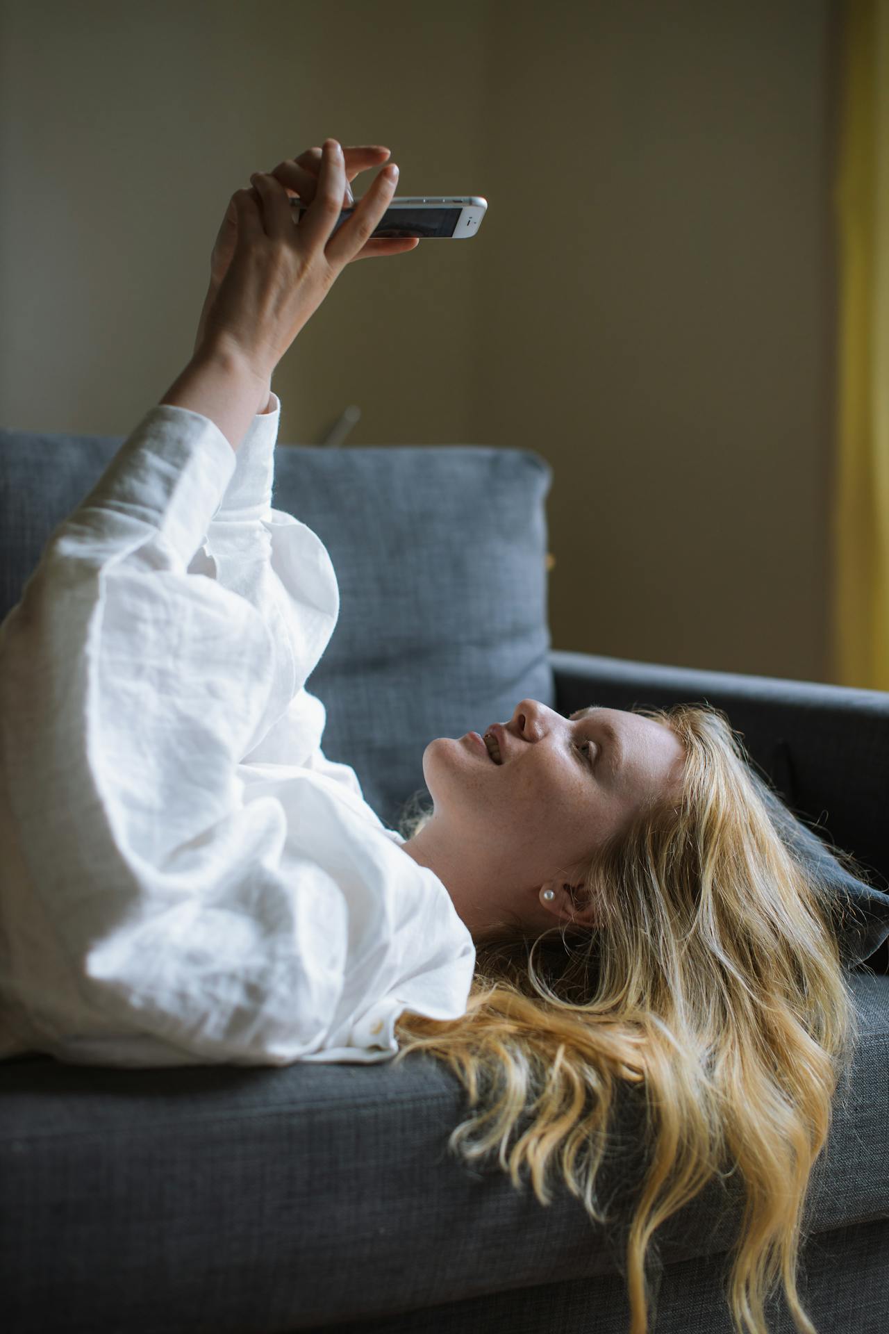 Eine Frau, die auf der Couch liegt und ihr Telefon benutzt | Quelle: Pexels