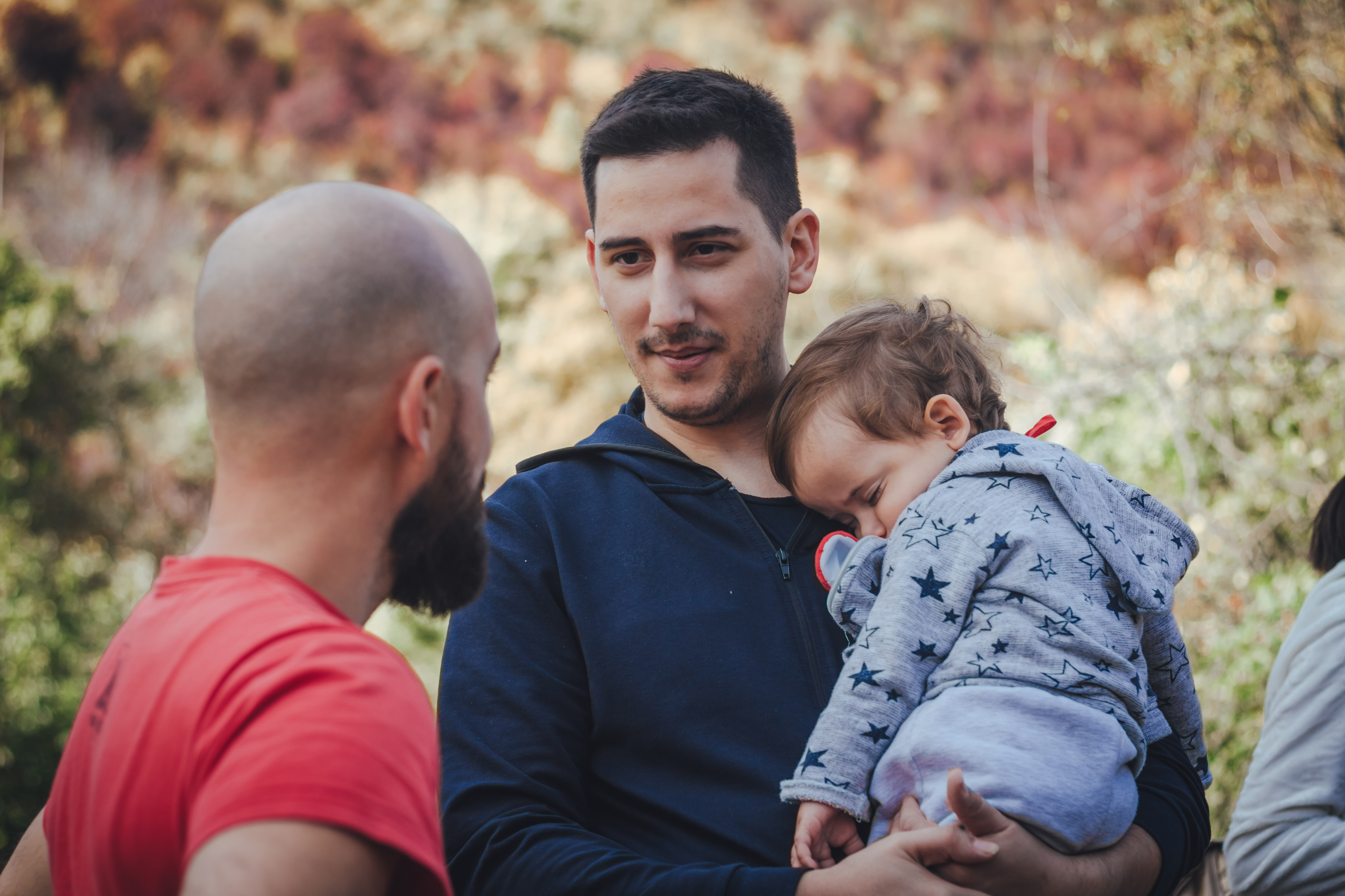 Zwei Männer unterhalten sich und einer von ihnen hält ein Baby | Quelle: Shutterstock